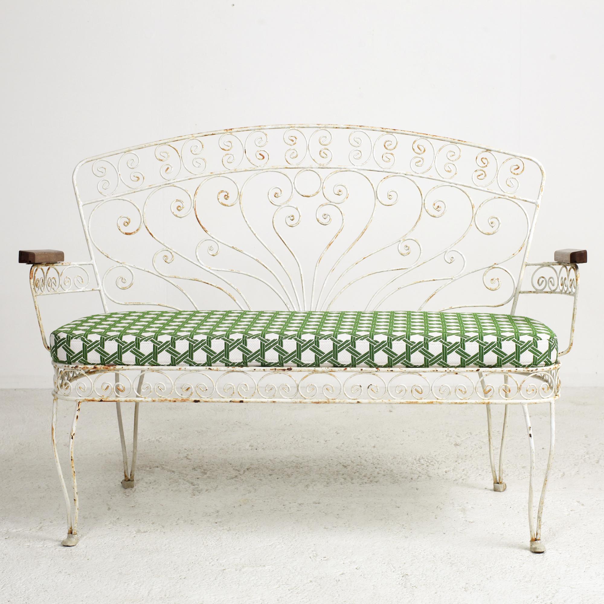 Fantastic French wrought iron and wire garden patio settee or bench. The piece feature wrought iron frames with many ornamental wire trim adorned with arabesques, scrolls and solid oak armrests.
Original vintage condition, structurally sound and