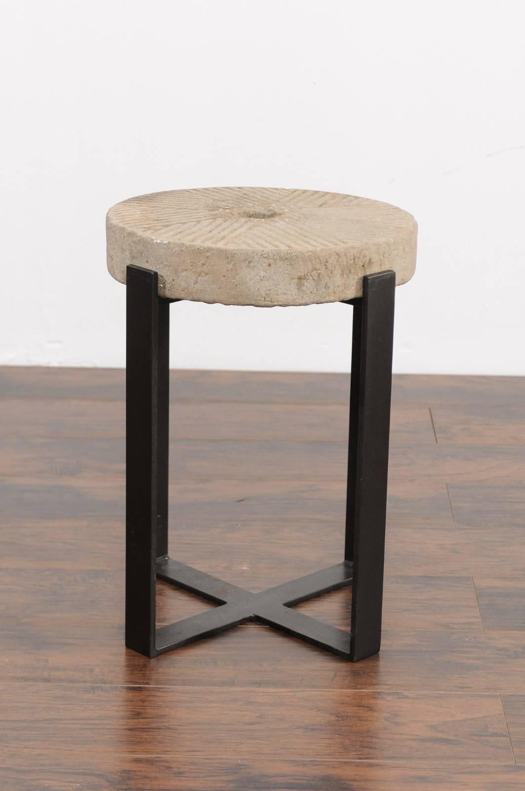 An old French millstone drink table mounted on a new custom-made iron base. We currently have two tables available, priced and sold individually. This charming drink table features an old early 20th century millstone top, adorned with the typical