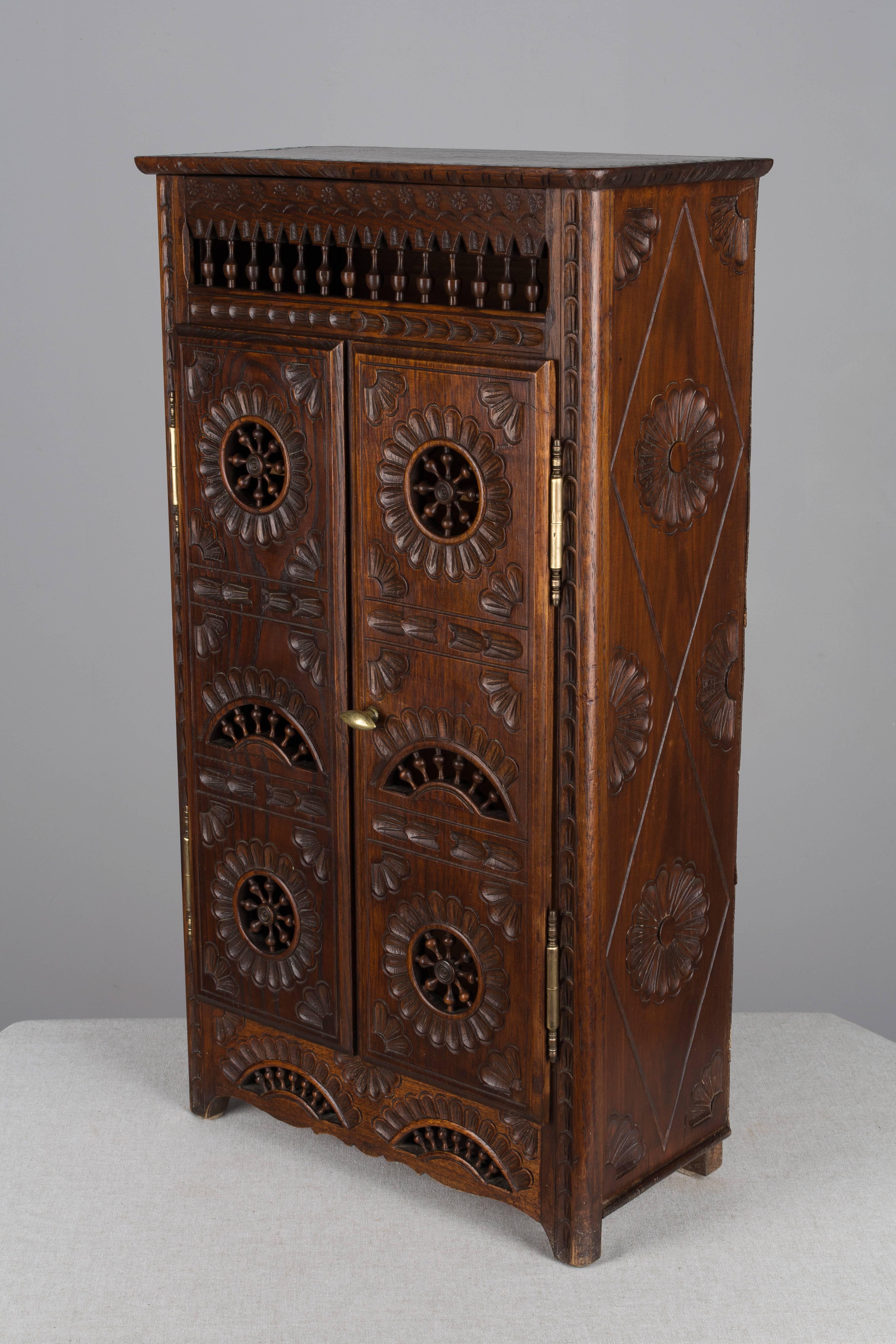 A large-scale French miniature armoire from Brittany, made of dark stained oak and elaborately decorated with hand-carved and incised details. May be used freestanding or as a wall cabinet.  Inside depth is 7