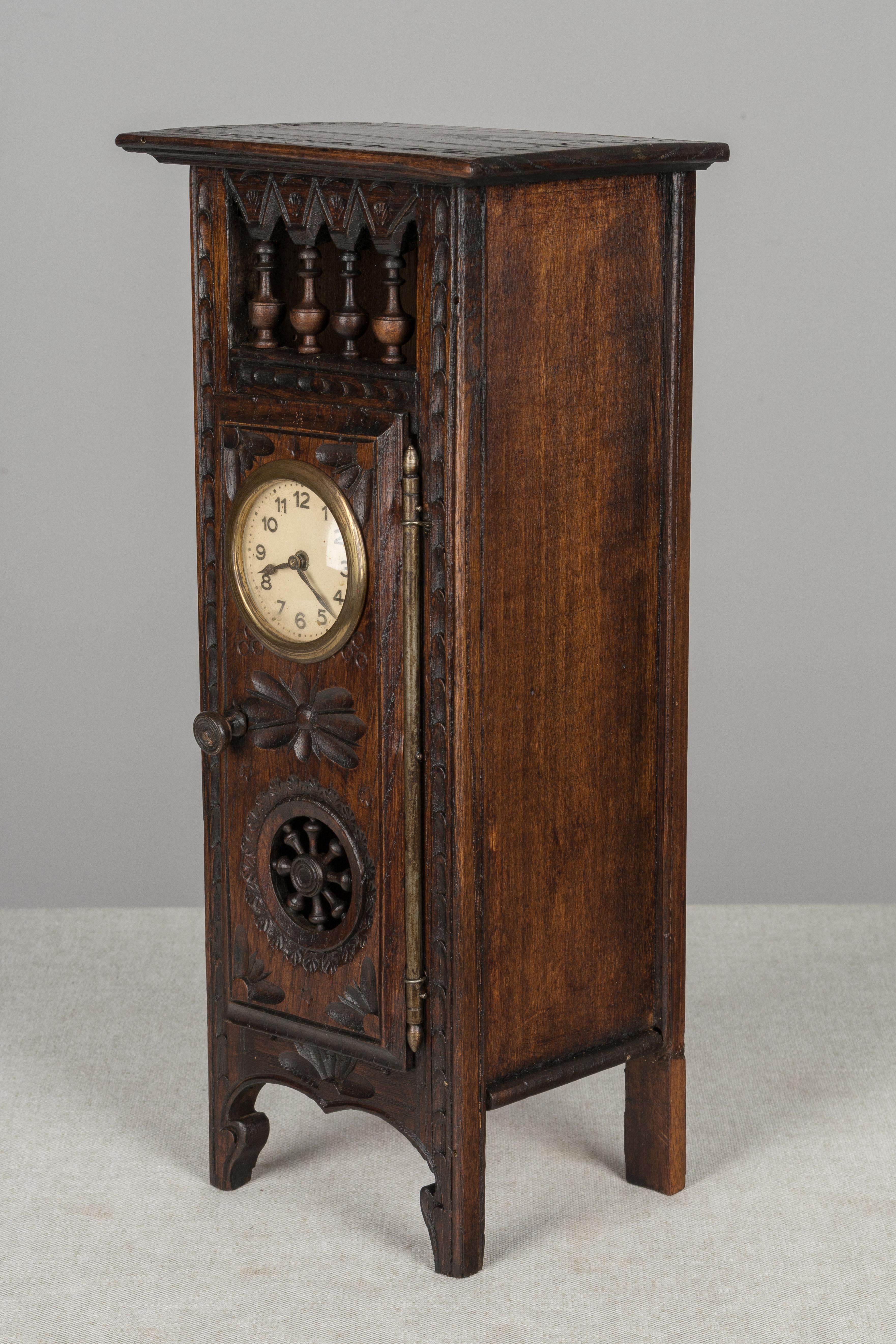 A French miniature grandfather clock from Brittany made of dark stained oak and elaborately decorated with hand carved and incised details. Not in working order. A back leg has been restored. We have a selection of Brittany miniatures included an