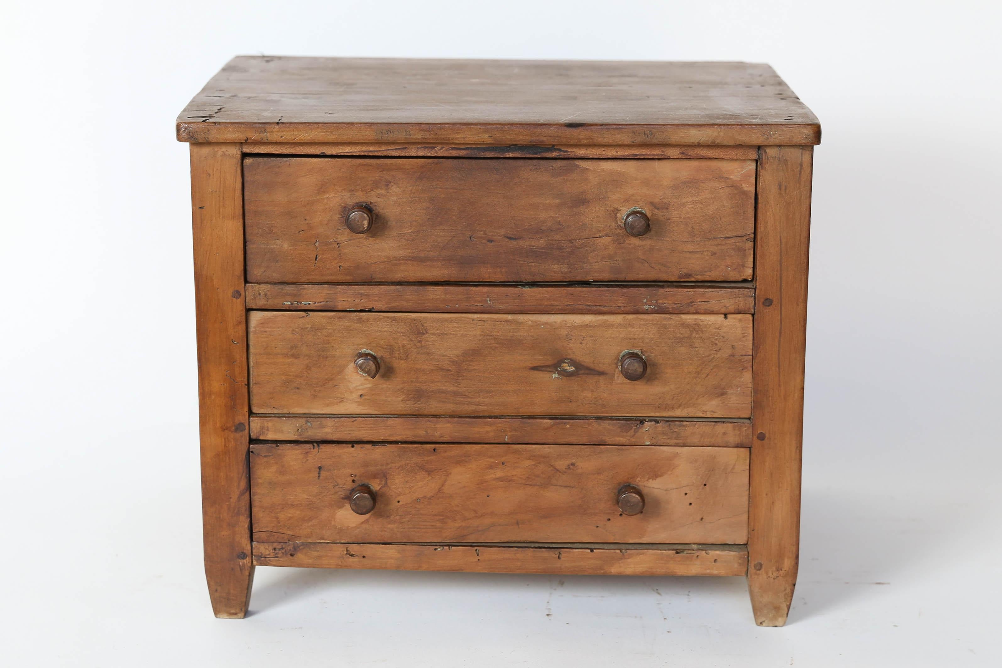 A lovely three-drawer model chest found in France. Two small knobs on each drawer and small proportions give this model chest warmth and charm. The carving on the back of two initials and a heart lead us to believe it was a marriage gift at one