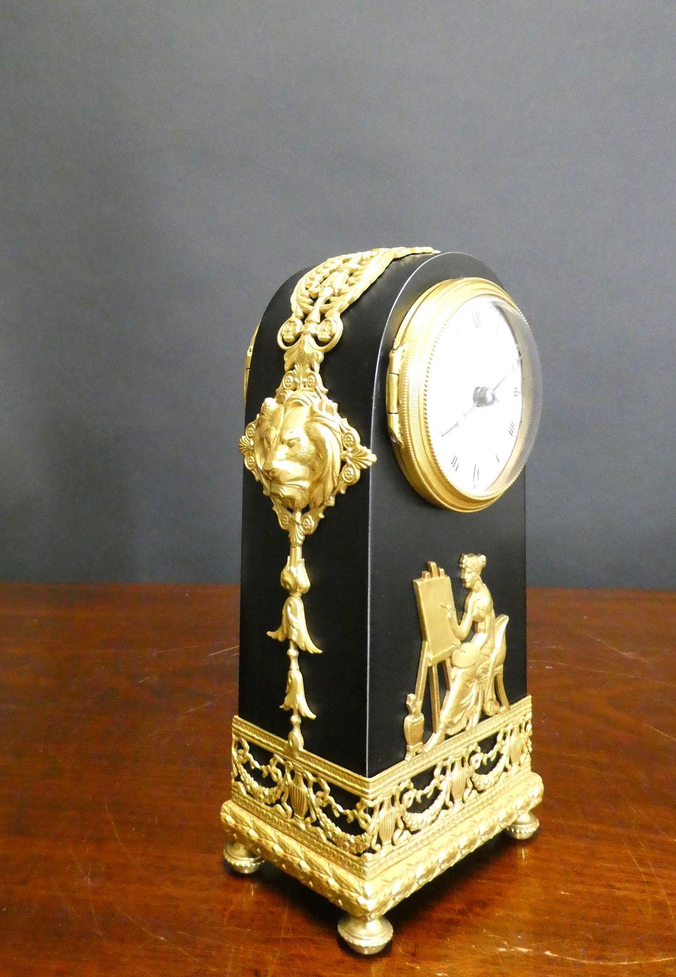 French Miniature Mantel Clock

Miniature French mantel clock housed in a patinated bronze arch top case with beautifully cast ormolu mounts depicting a maiden at her easel and classical urn decoration. Lions head applied ormolu mounts to the sides