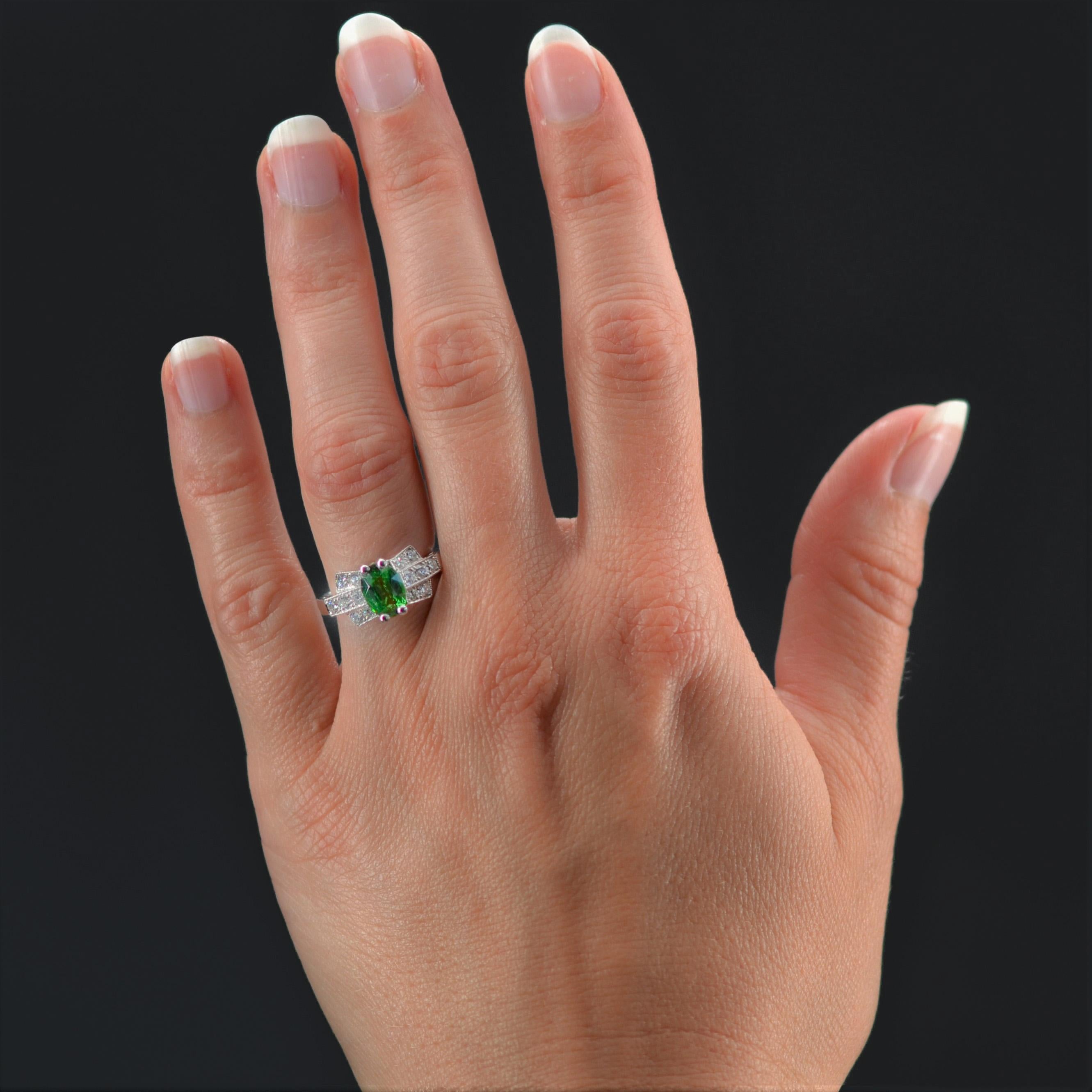 Ring in platinum, dog head hallmark.
Superb ring inspired by art deco, it is set with claws of a bright green tsavorite garnet. On both sides, a geometric decoration is formed by 3 lines of modern brilliant- cut diamonds.
Total weight of the garnet
