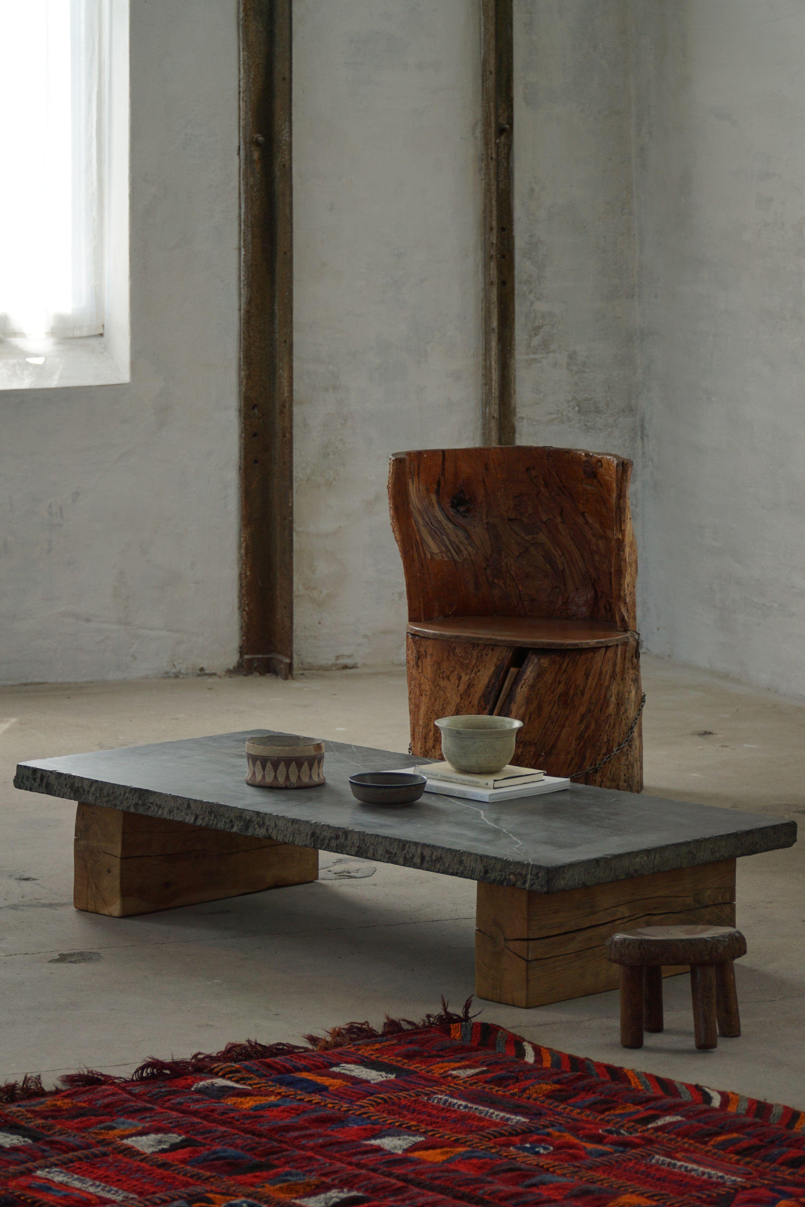 A striking example of mid-century French Modern design, this low coffee table from the 1960s embodies the raw, geometric essence of Brutalism. The table features a substantial rectangular natural stone slab top.
Supporting the monumental top are two