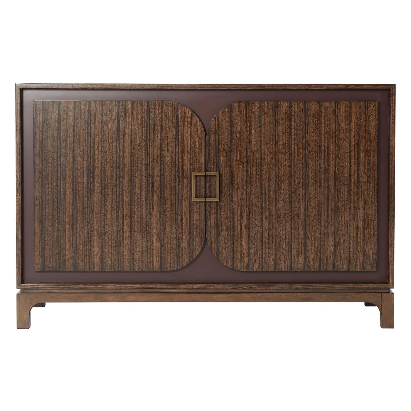 French modern cabinet with quartered Paldao veneered case with a hazelnut finish, burgundy lacquered recessed door background with floating square brass handles with adjustable shelves to the interior.
Dimensions: 52