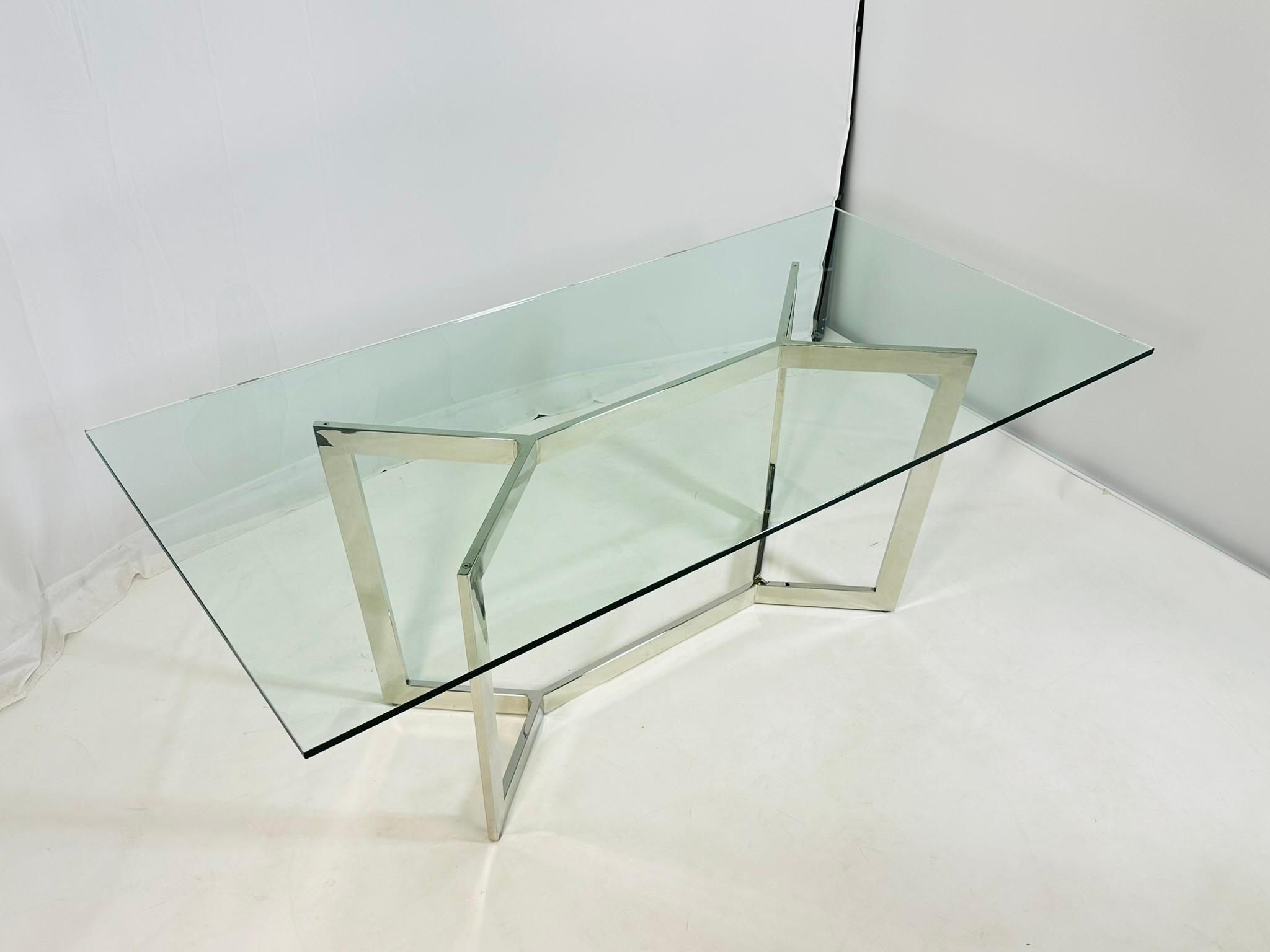 Llamativa mesa de comedor moderna francesa al estilo de Paul Legeard, del siglo XX. Esta elegante pieza presenta una escultural base de cromo pulido de atrevidas líneas angulosas, que sostiene una importante tapa rectangular de cristal. La forma