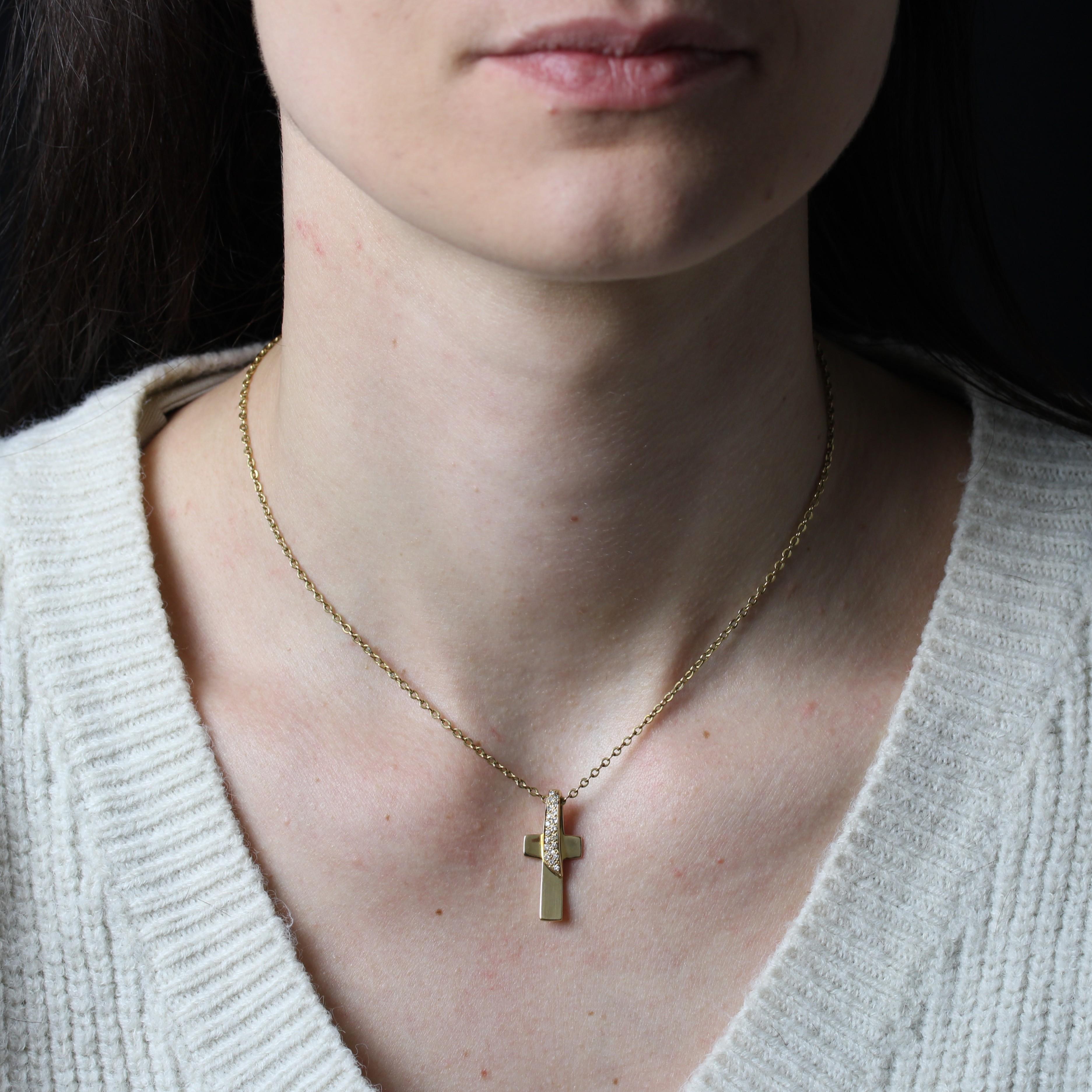Cross in 18 karat yellow gold, eagle head hallmark.
A smooth, slightly concave yellow gold cross with a folded link at the top, adorned with brilliant-cut diamonds forming the hanger. The hanger is located at the back of the pendant.
Total weight of
