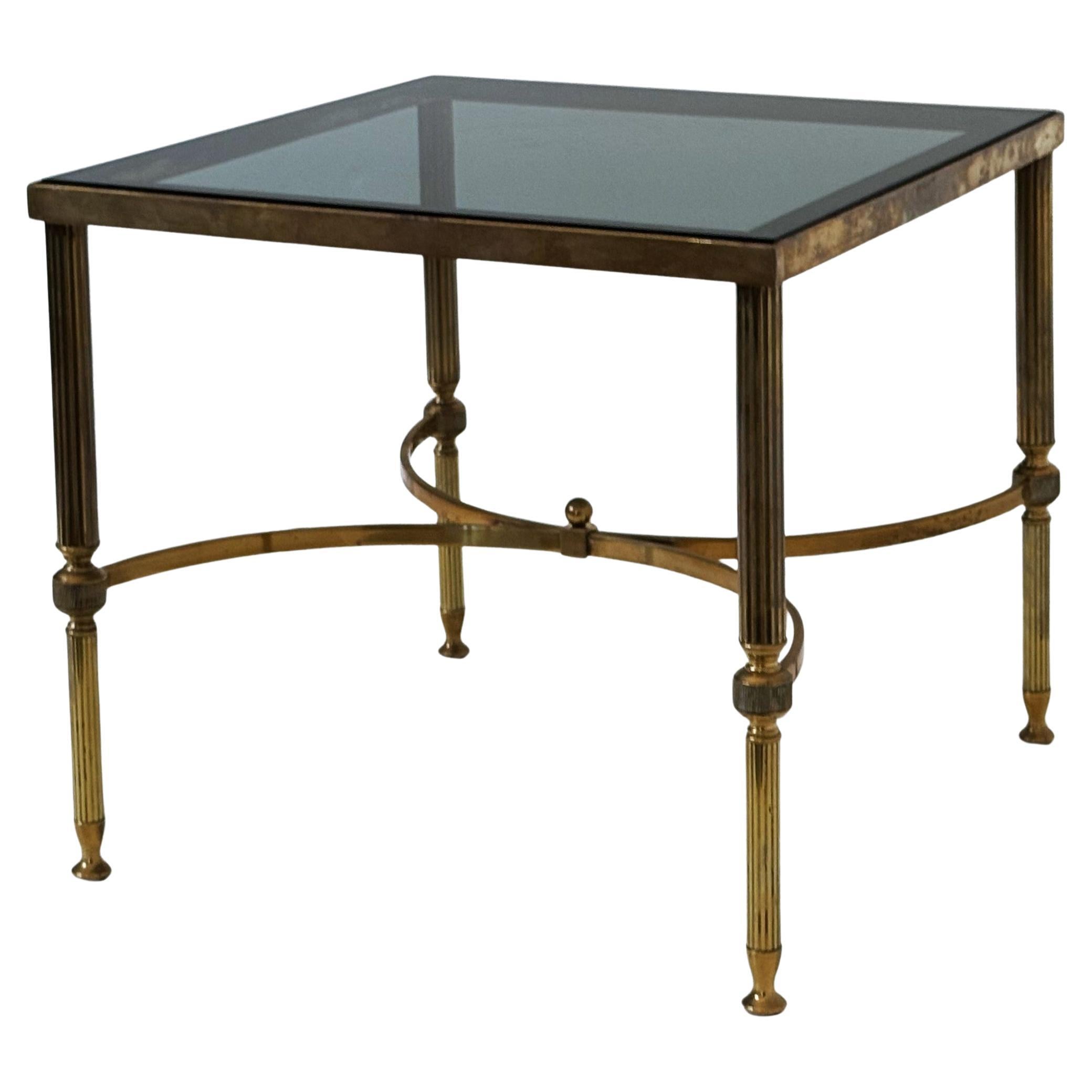 A pair of fine French Modern low square end or coffee tables in a Maison Jansen style - each featuring an inset smoked glass panel top. over a  frame with finials and reeded legs of brass. 
The burnished brass exhibiting a patina that suggests age