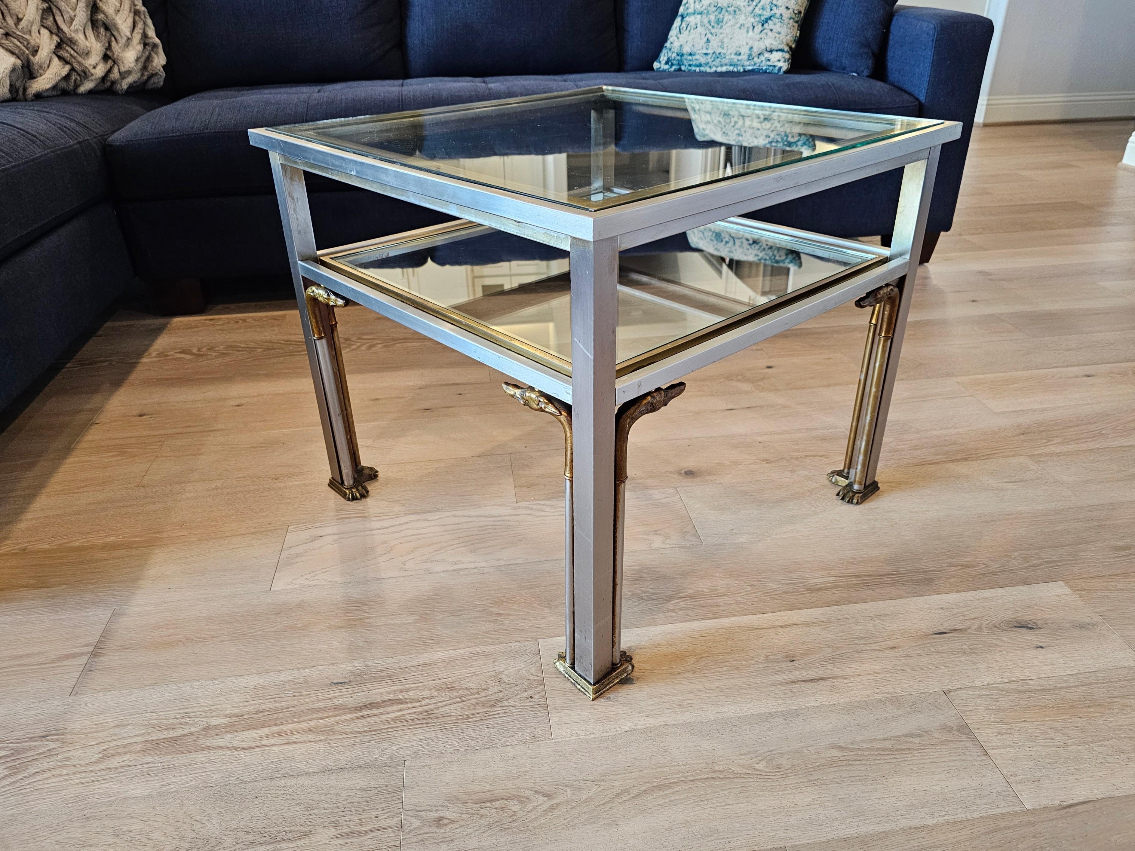 A stunning rare midcentury French mixed metal two-tier table attributed to luxury Parisian design house Maison Jansen (Paris, France; 1880-1989)

Mid-20th Century, having a patinated silver-tone brushed steel frame, gilt metal accents, featuring