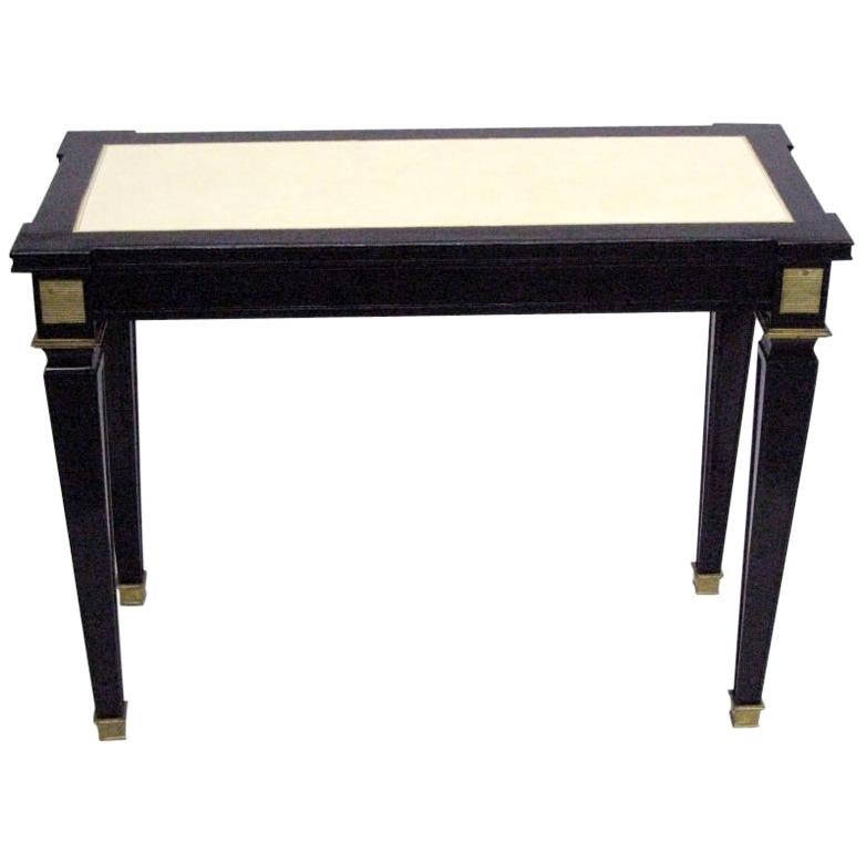 An Elegant French Mid-Century Modern Neoclassical black lacquered console or sofa table attributed to Andre Arbus with exquisite tapered legs, solid brass moldings and brass sabots. The top is inset with cream leather and creating a color and