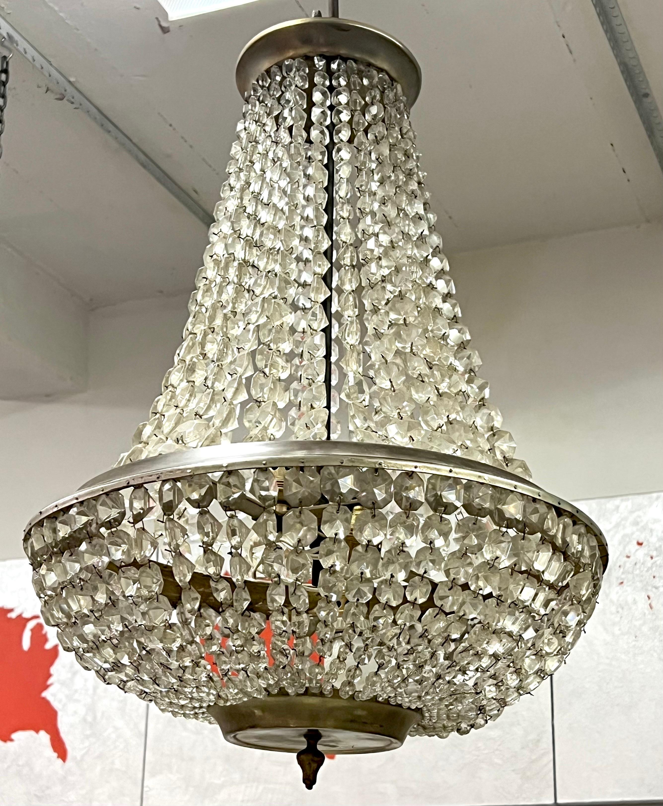 An elegant, sober French Mid-Century Modern Neoclassical / French Late Art Deco cut crystal chandelier attributed to Maison Bagues, Paris, 1930. The piece has an eye-pleasing, classic, bell shaped form and its crystals shine with a clear, diamond