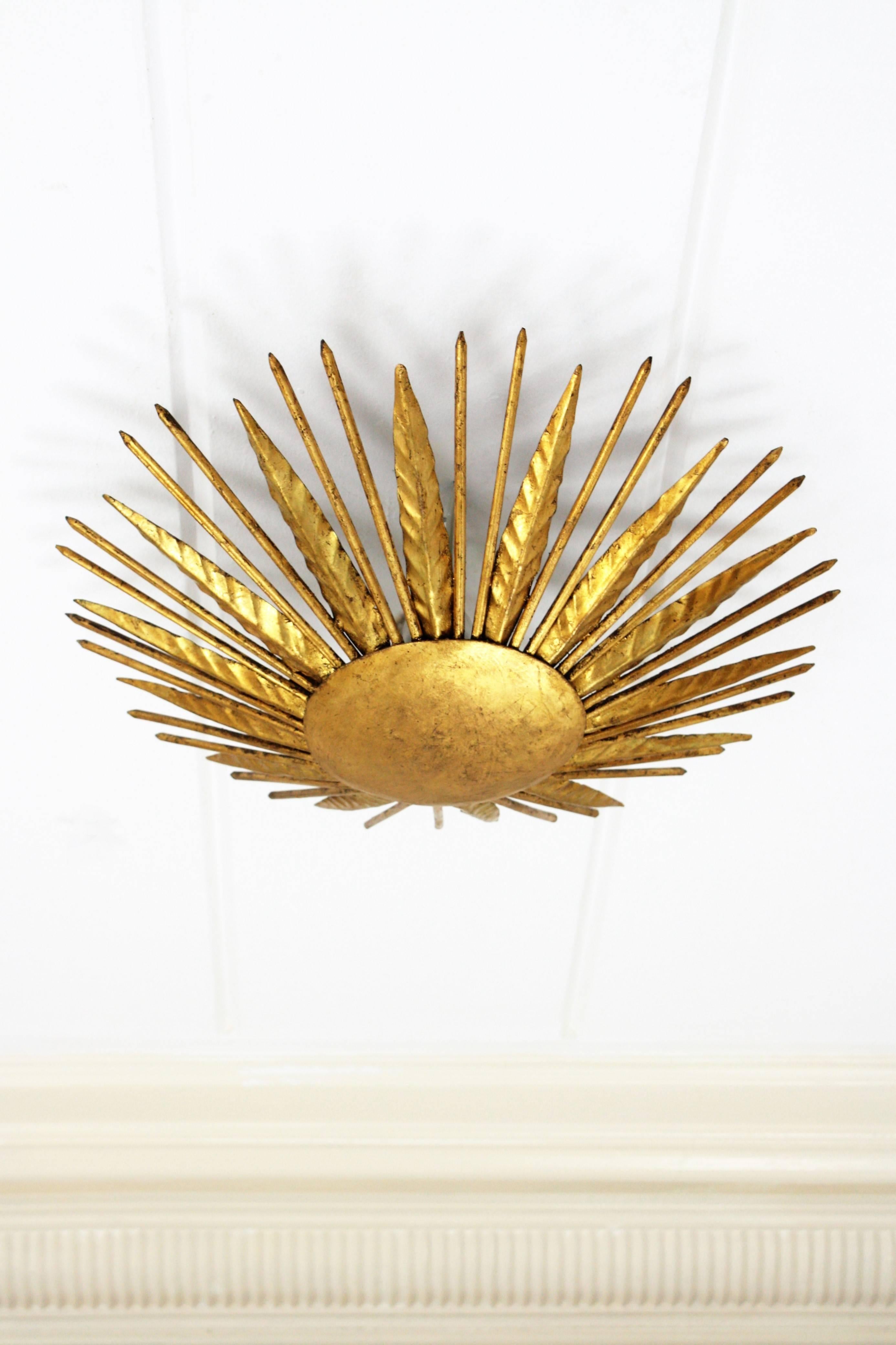 Hand-hammered gold leaf gilt iron sunburst light fixture from the late Art Deco period, France, 1940s.
This piece is highly decorative due to its design, alternating iron leaves with pointed spikes. This light fixture can be hung as a wall or