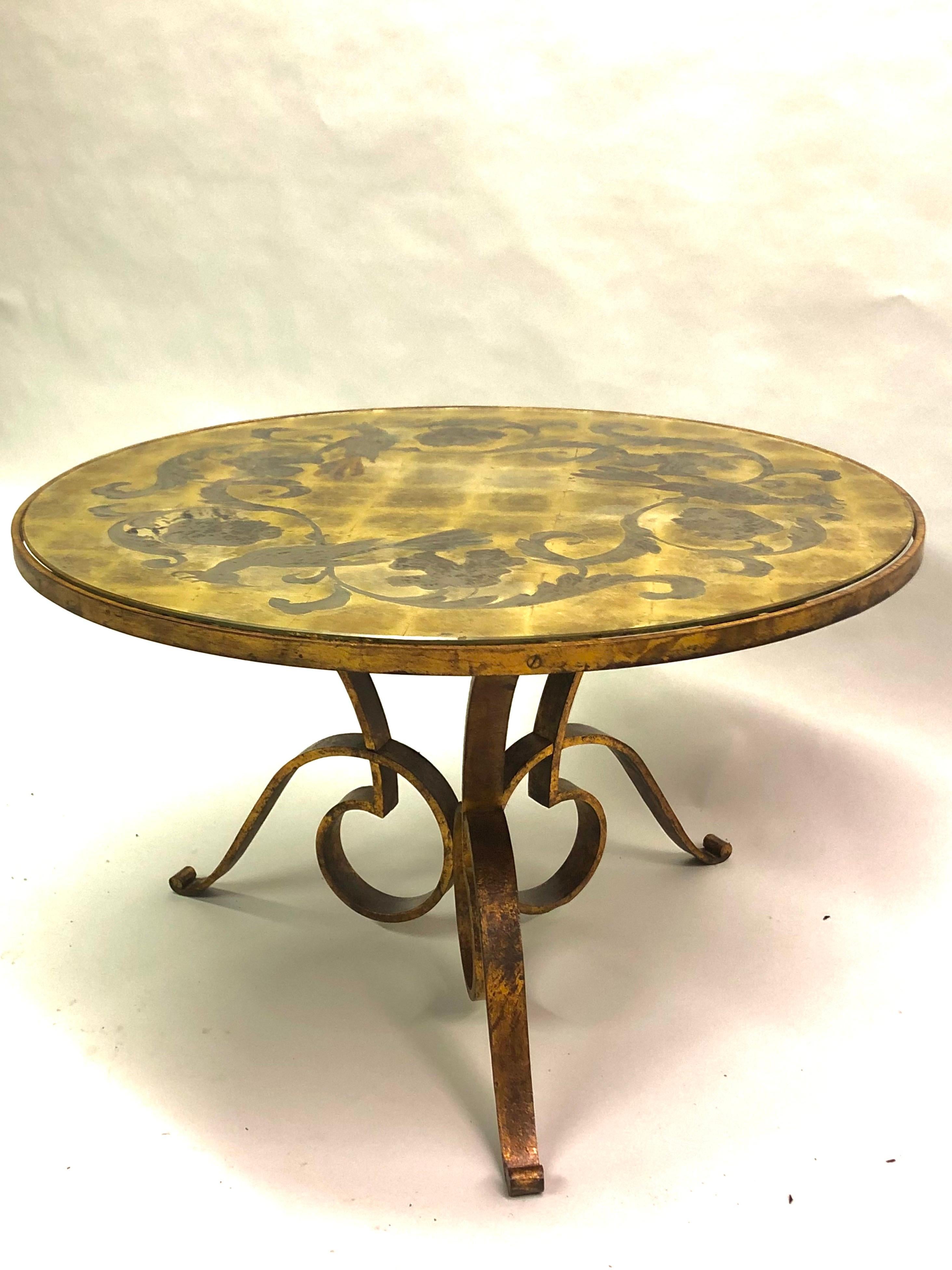 An Iconic French Mid-Century Modern Neoclassical gilt wrought iron round cocktail table or side / end table by Rene Drouet, France, 1940. The piece has an enchanting form with dynamic, lyrical curves The poetic tripod form base is in gilt hand