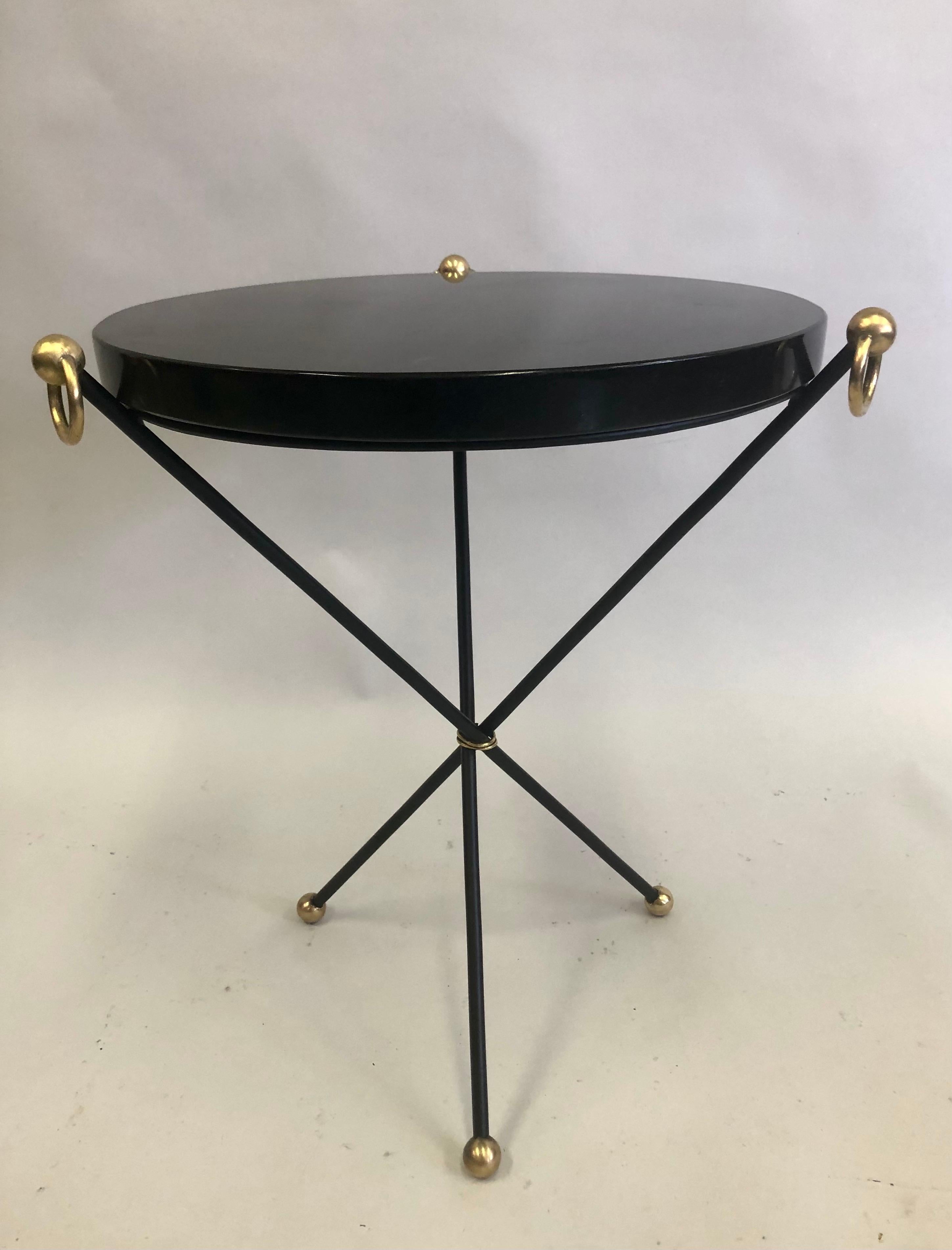 Elegant French Mid-Century Modern neoclassical Guerdon, side or end table attributed to Jacques Adnet.
The table is set in a classic tripod form in enameled wrought iron with an deeply inset mottled black stone top. Rich polished brass ball feet, 3