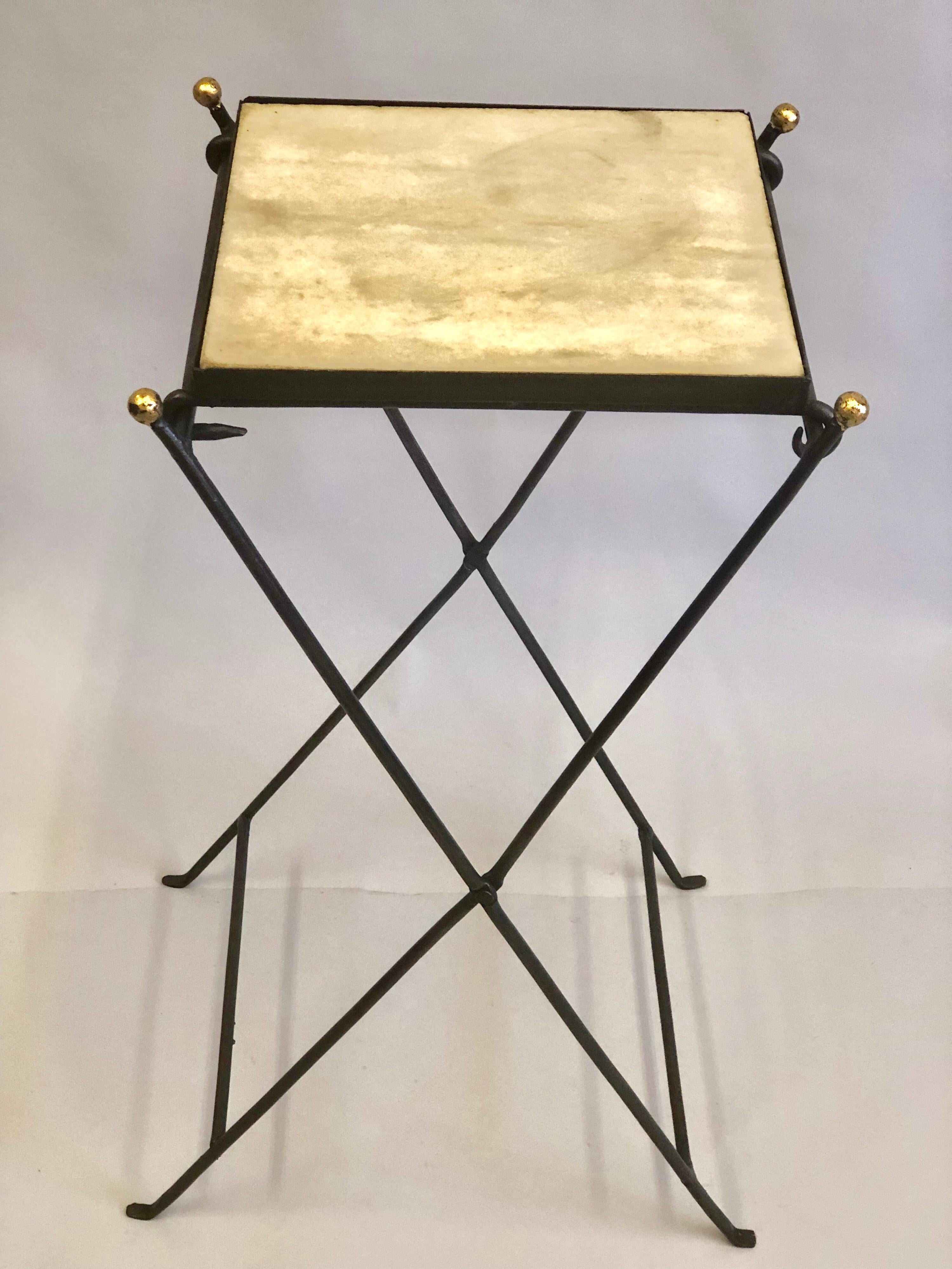 Elegant and unique French midcentury partially gilt wrought iron and marble folding side table or gueridon in the manner of Jean Michel Frank, circa 1935.

Though the folding 'campaign' table is composed of hammered iron and stone it is light and
