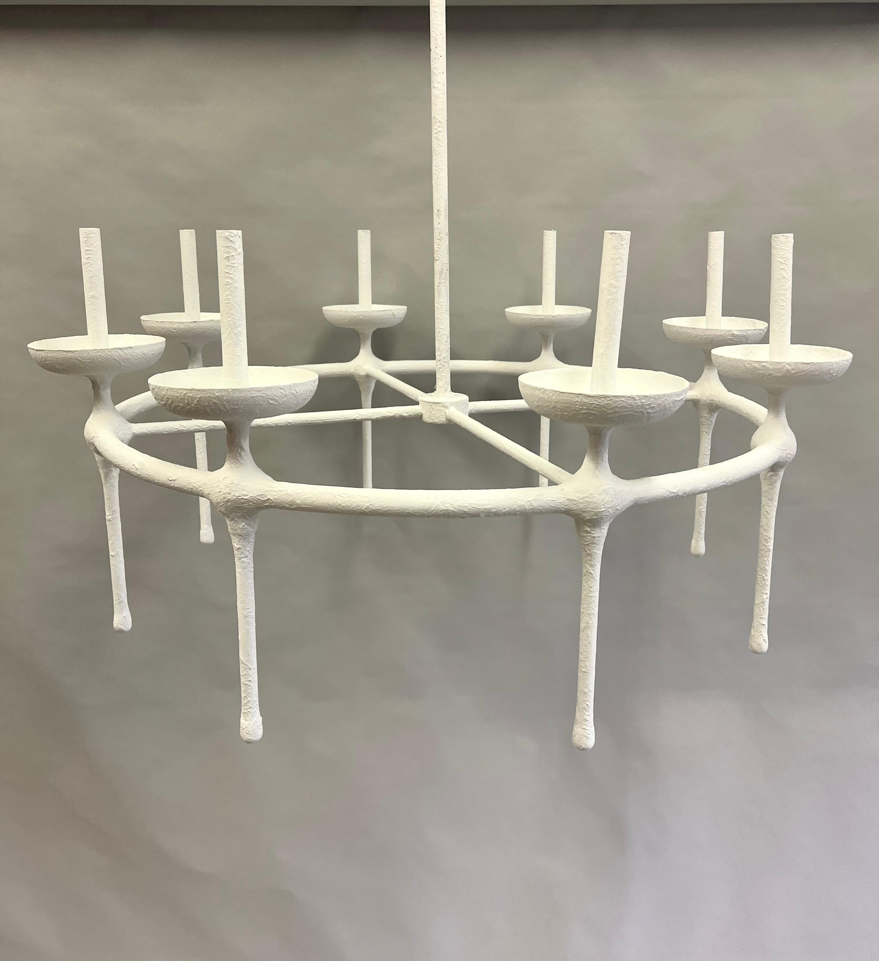 Elegant and iconic French Modern Neoclassical chandelier in the style of Alberto and Diego Giacometti. The form is sublime. It is composed of a cylindrical iron base from which 8 torch lights are suspended and united around a cross form stretcher.