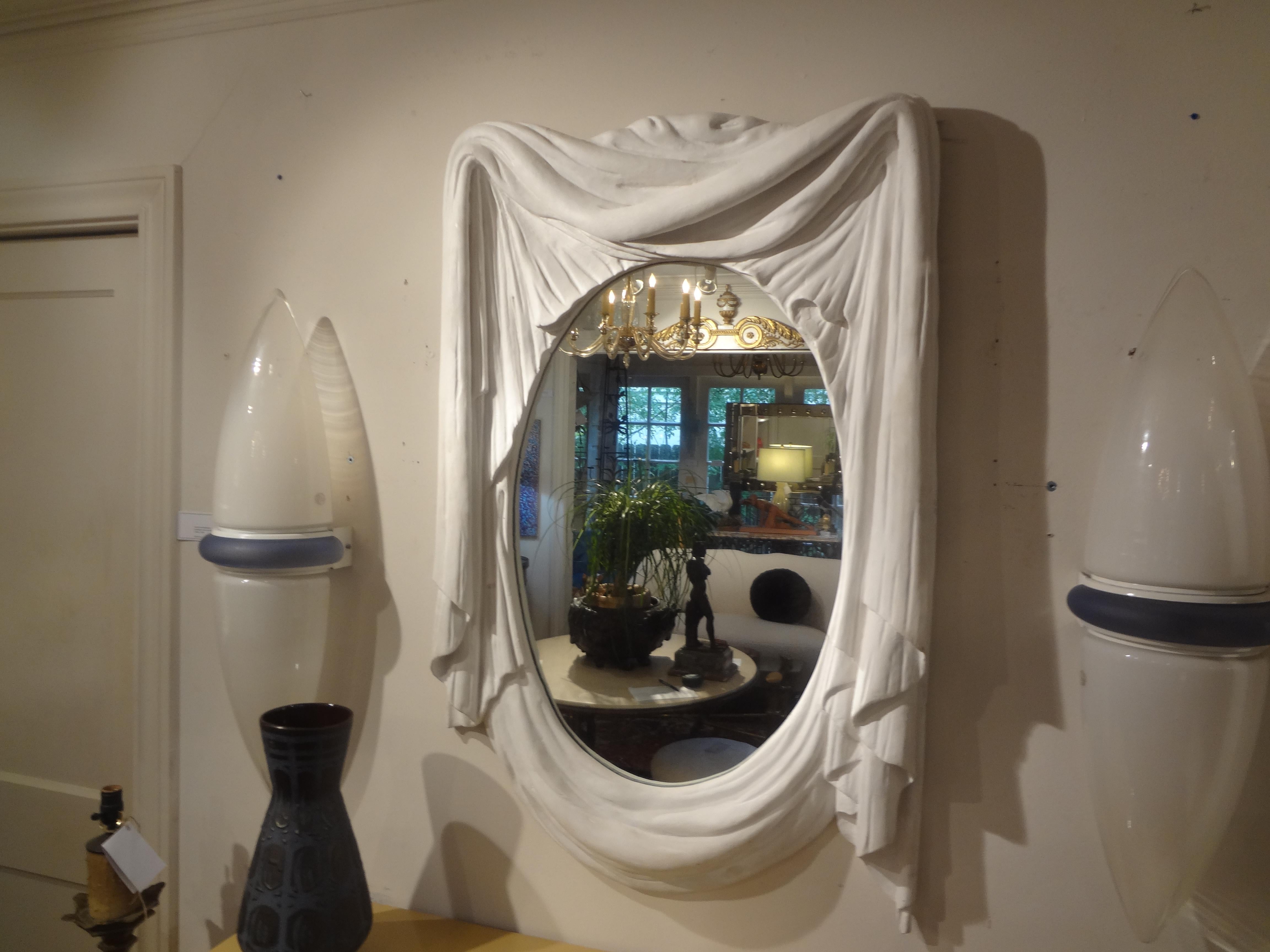 French Modern Plaster Draped Mirror in the Manner of Serge Roche.
This outstanding French plaster mirror has a beautiful asymmetrical draped or swag design with a central oval mirror plate. 
This stunning Parisian style French plaster mirror is in