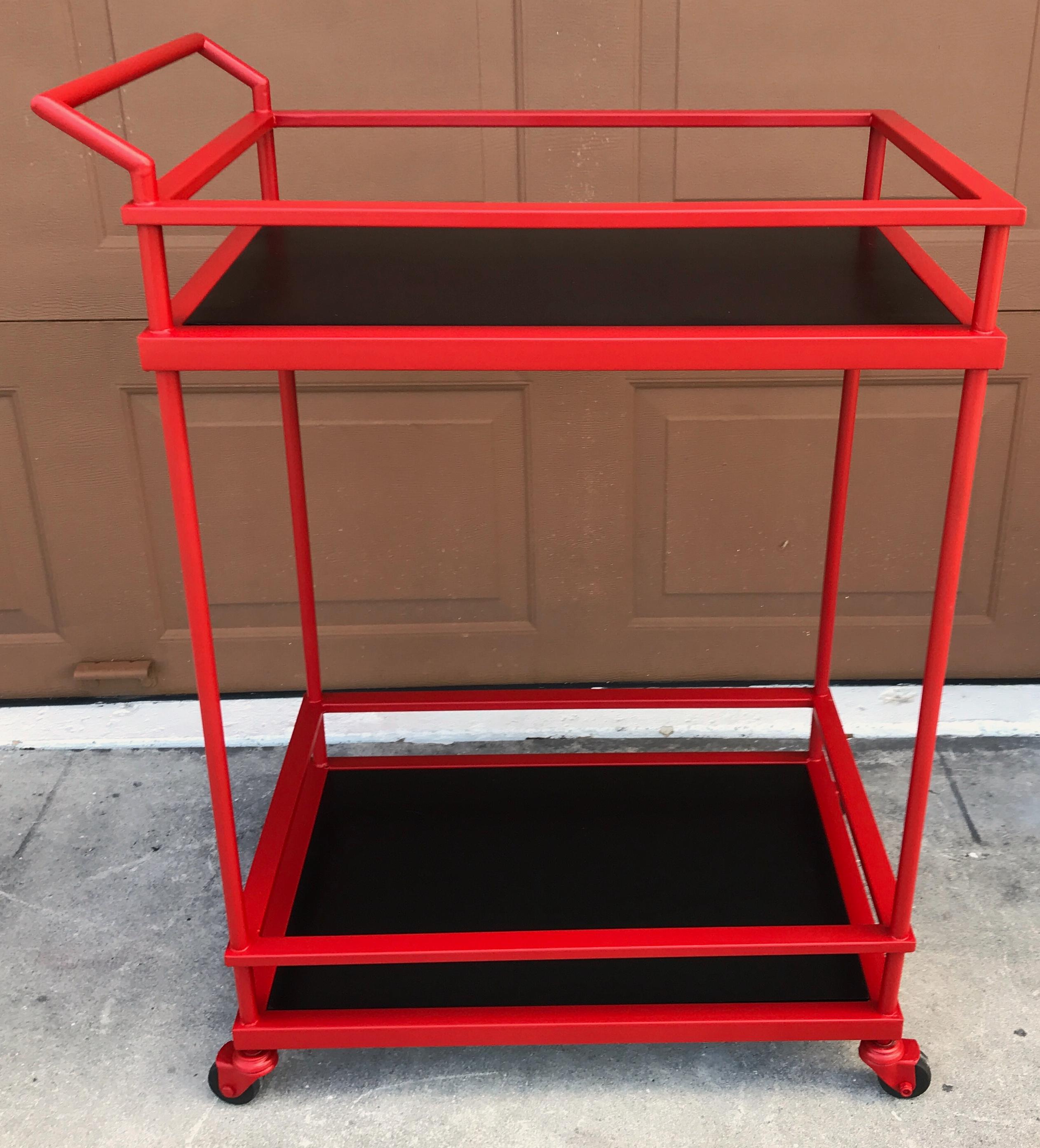 French modern red enameled bar cart, with two galleried tiers, and inset black lacquered panels. Raised on four wheeled castors.