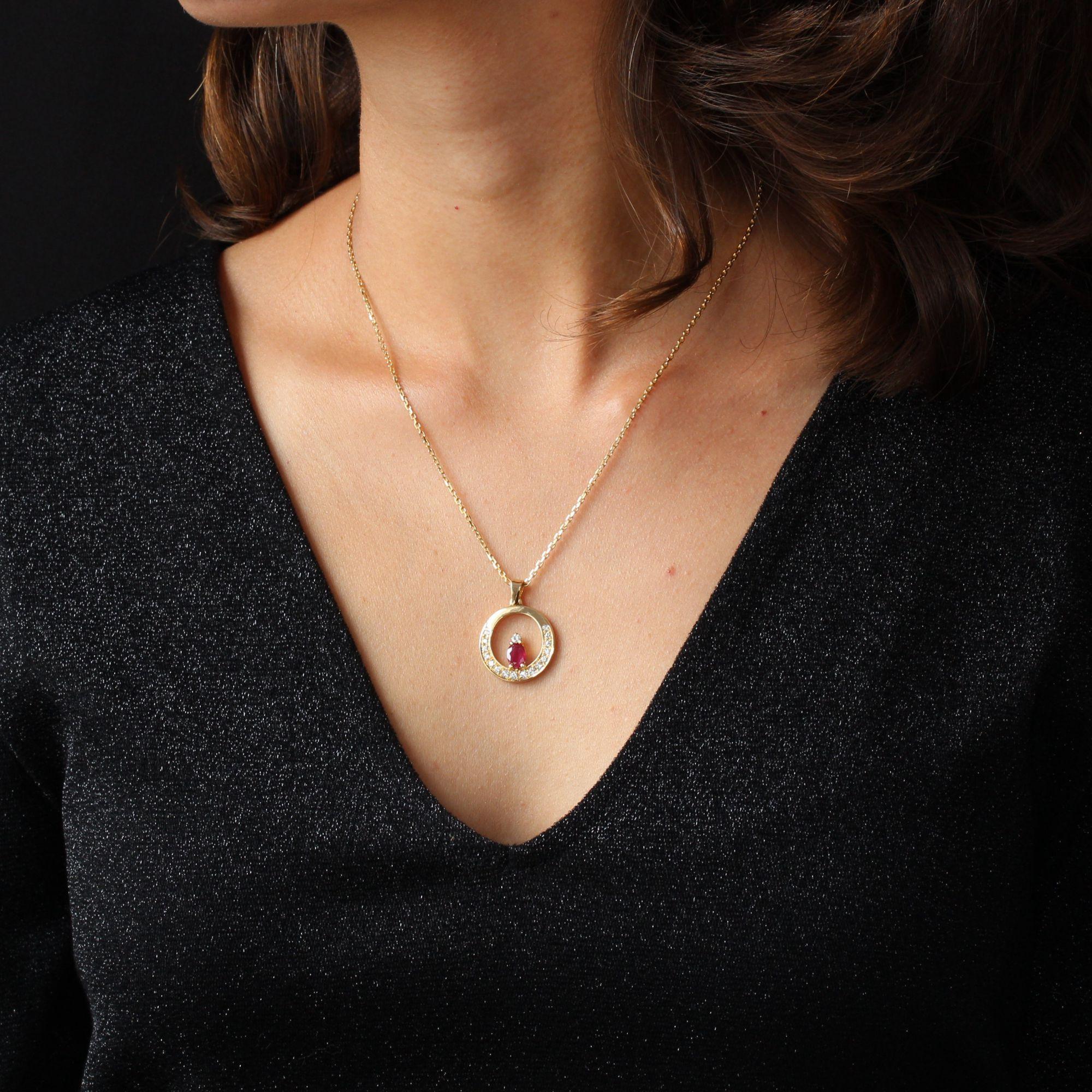 Pendant and its chain in 18 karat yellow gold, eagle head hallmark.
This round gold pendant is openwork in its center, set with modern brilliant-cut diamonds on 3/4 of its wire, and in its center an oval ruby is set with 4 claws, topped by a modern