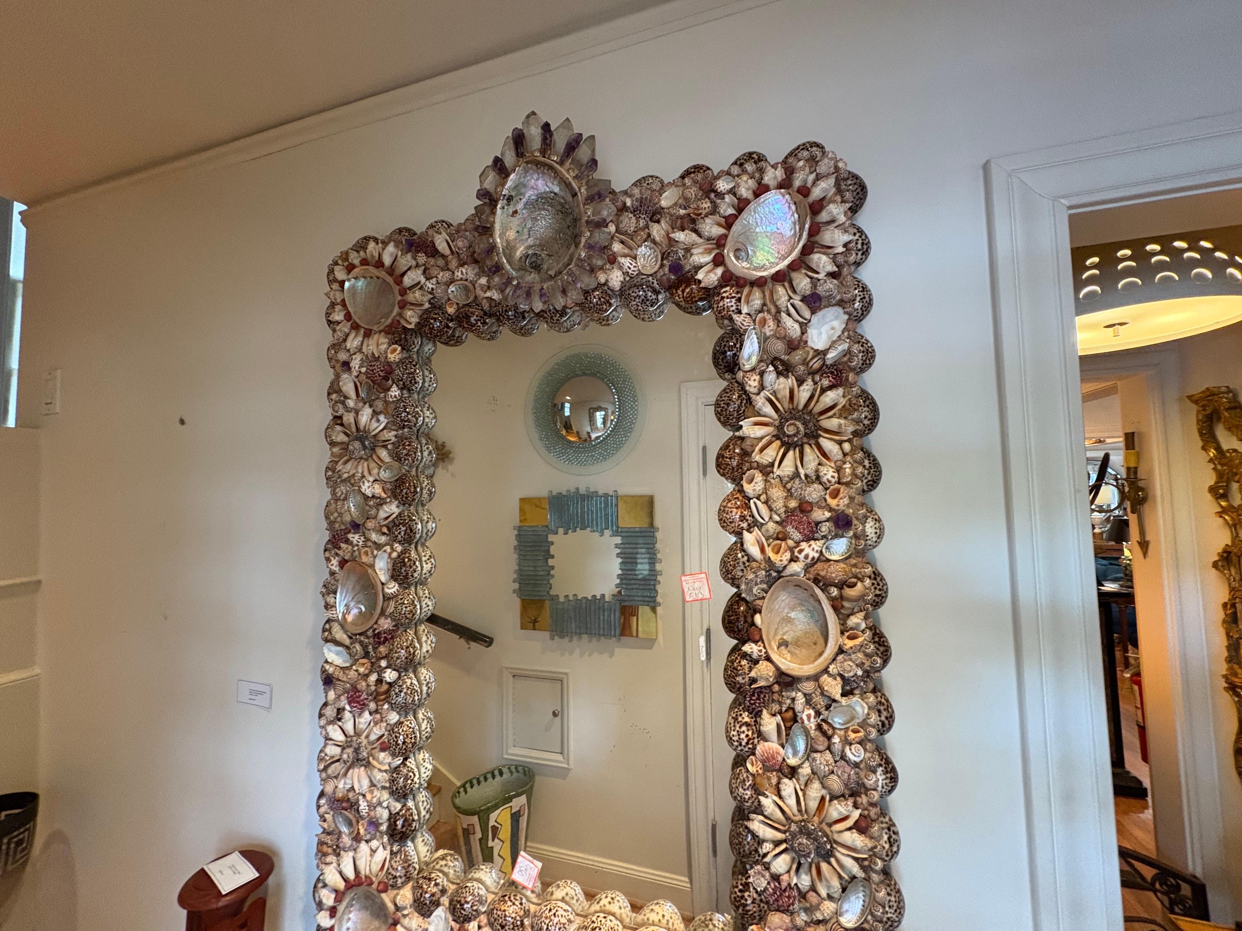 Spectaculaire miroir moderne français en coquillage, améthyste et cristal de roche.
Il s'agit d'un grand miroir rectangulaire Organic Modern French, stratégiquement incrusté d'une belle variété de coquillages, d'améthyste et de cristal de roche.
Ce