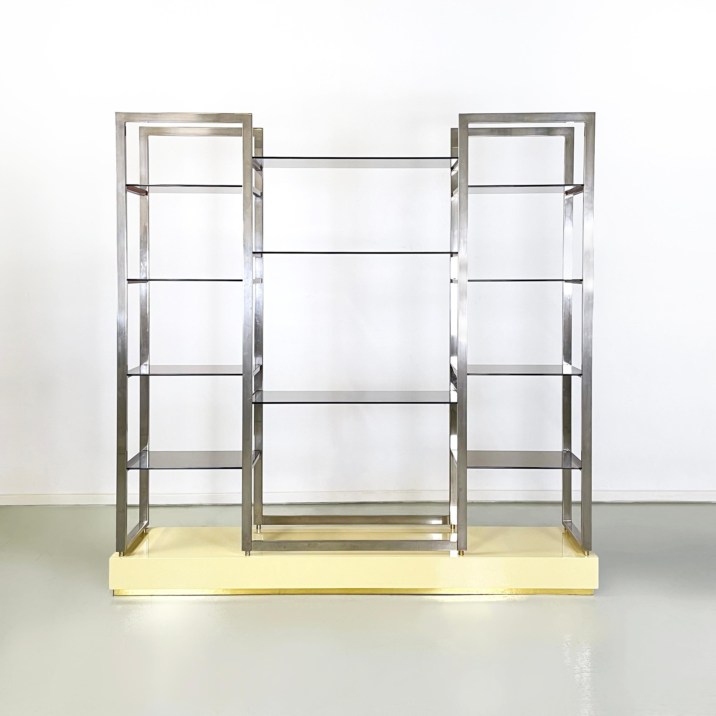 French modern smoked glass, metal and lacquered wood Bookcase by Alain Delon, 1980s
Self-supporting floor bookcase with a rectangular base in cream yellow lacquered wood and brass details. The bookcase features several smoked glass shelves, anchored