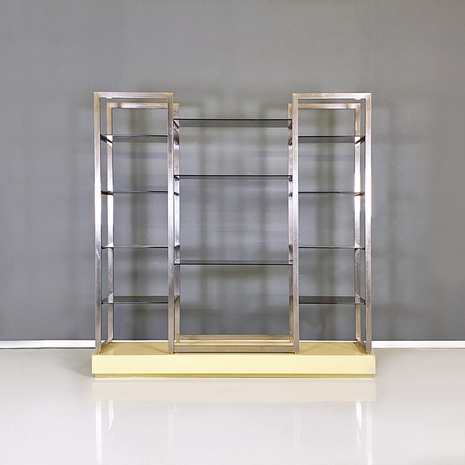French modern smoked glass, metal and lacquered wood Bookcase by Alain Delon, 1980s
Self-supporting floor bookcase with a rectangular base in cream yellow lacquered wood and brass details. The bookcase features several smoked glass shelves, anchored