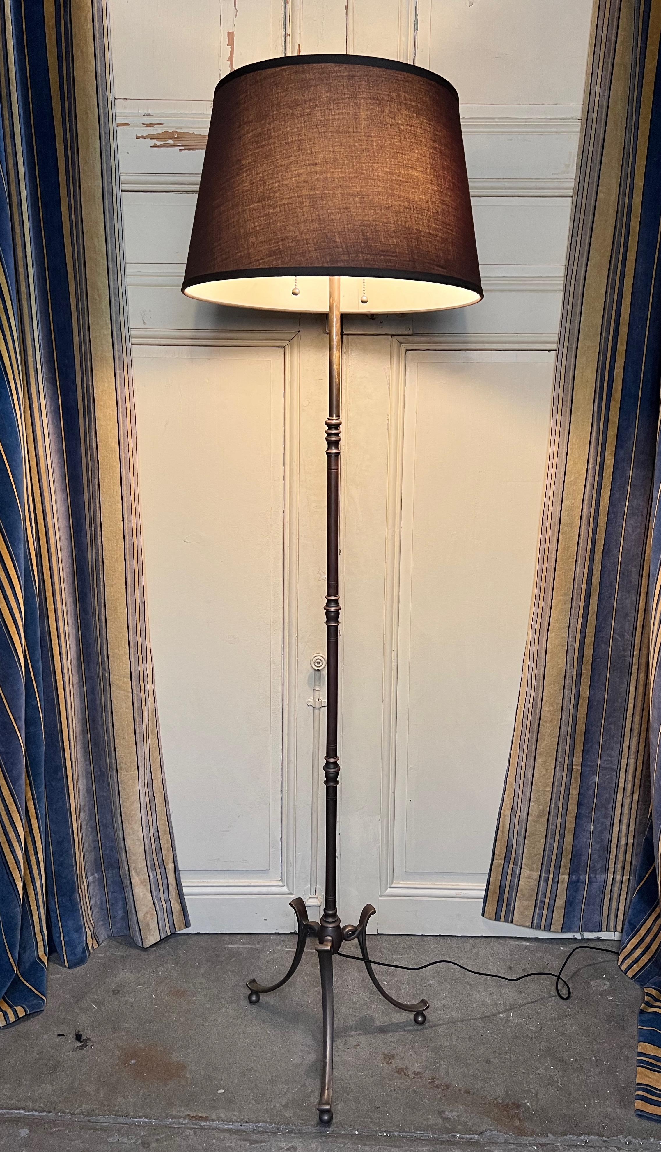 This elegant French floor lamp from the 1950s features a tripod base supported by balled feet, adding stability and style to its design. The stem of the lamp is beautifully finished in oil rubbed bronze, with turned accents that lend a traditional