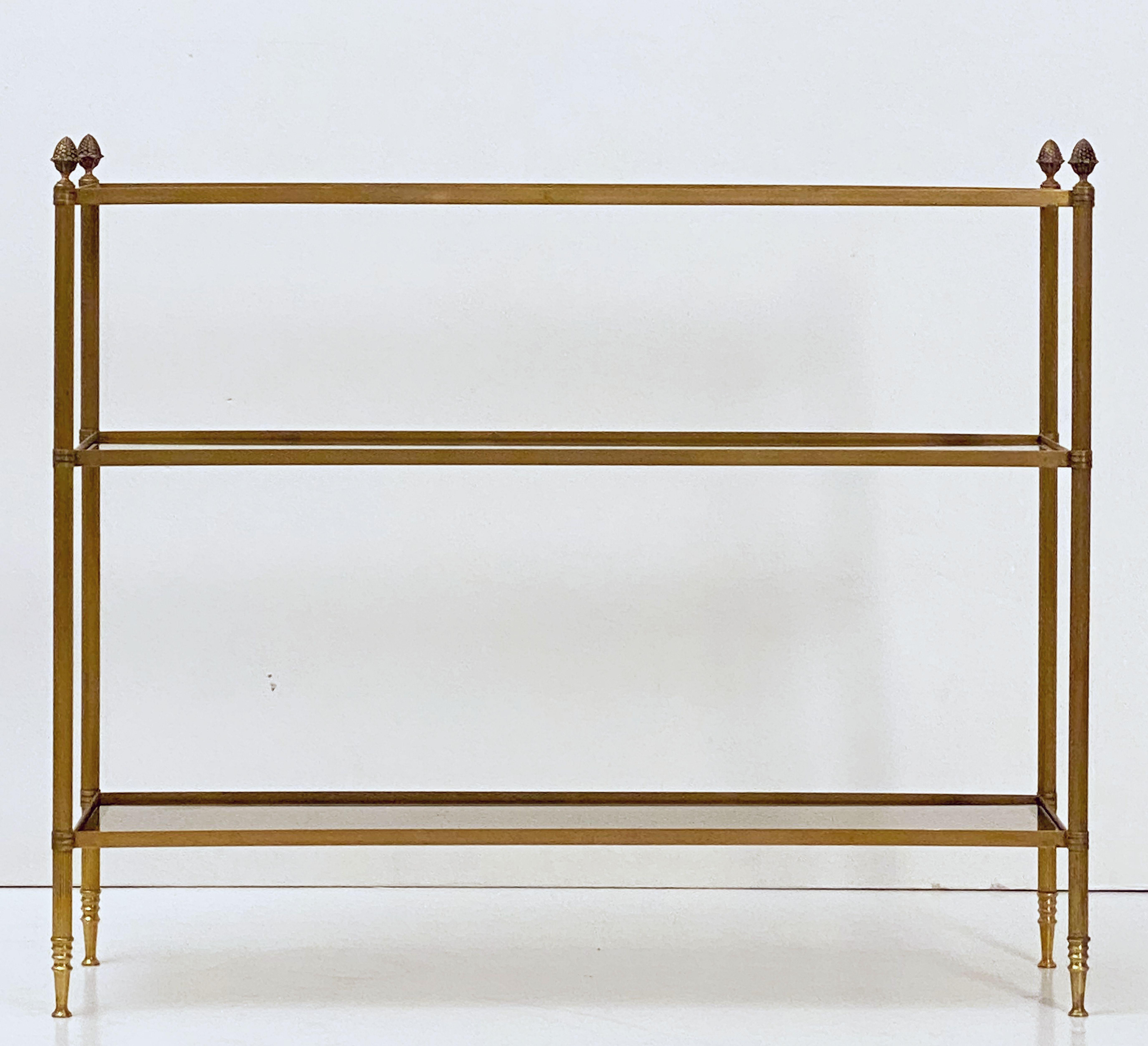 A fine French open étagère or display shelf - featuring a stylish modern brass frame with decorative finials and three rectangular shelves of smoked glass. 

Measures: Total unit height: 31.5 inches
Top tier or shelf height: 29.5 inches.