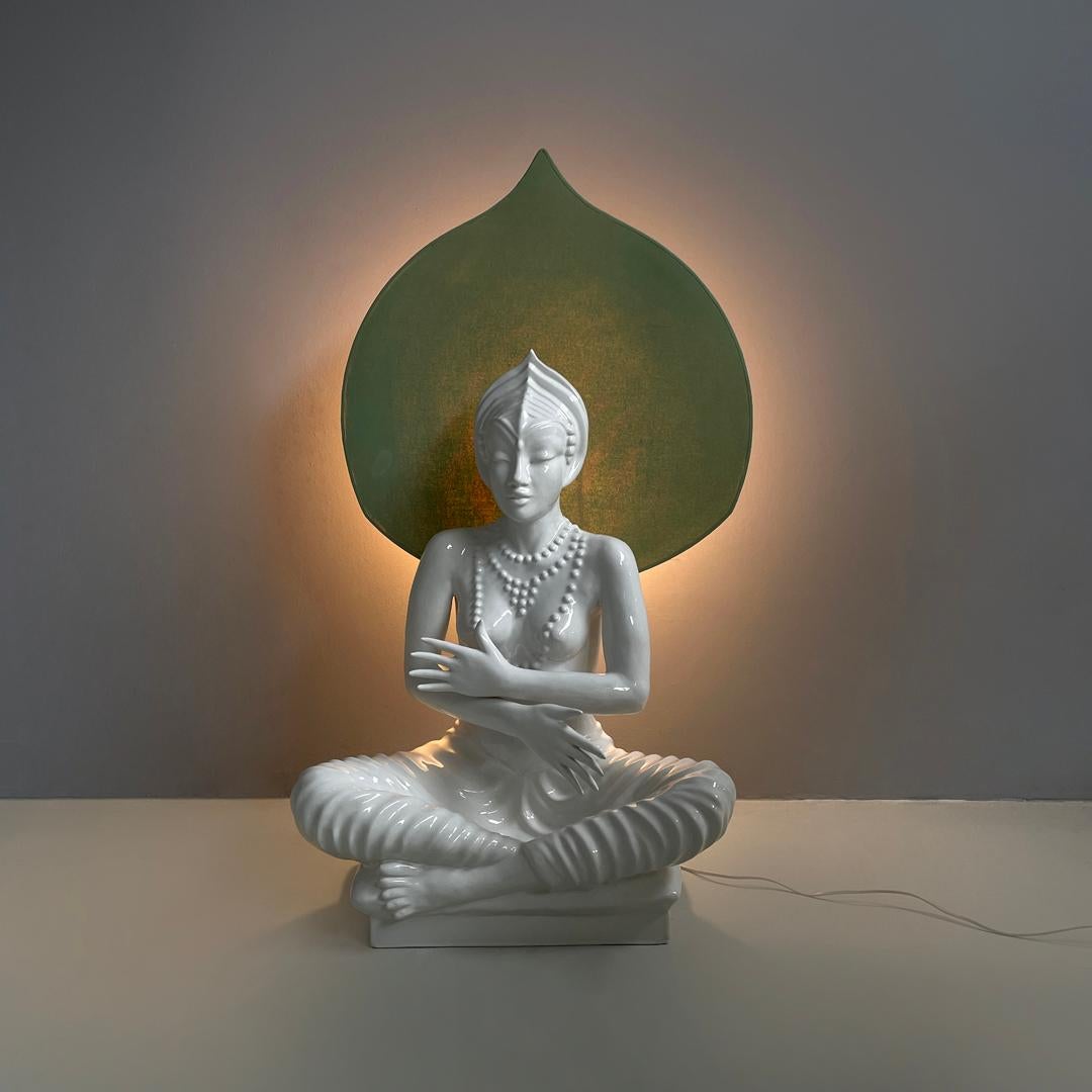 French modern white ceramic floor lamp with green leaf by Roche Bobois, 1980s 
White ceramic floor lamp with glossy finish. The structure represents a human form reminiscent of an oriental deity, sitting cross-legged, decorated with a headdress and