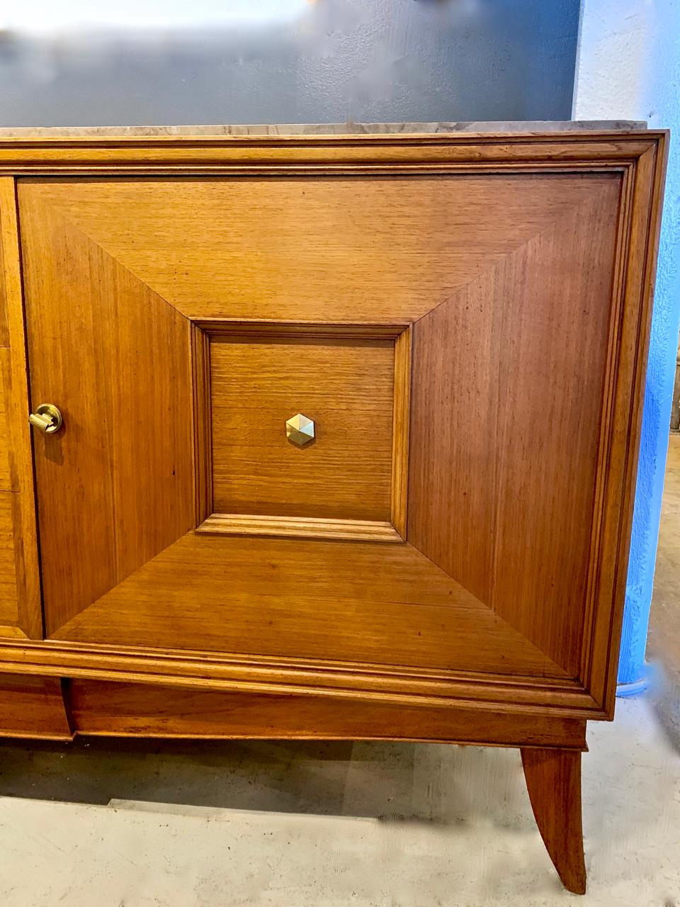 This is a wonderful example of a Moderne Enfilade or sideboard that dates to the 1950s. The Enfilade was crafted of Fine walnut, marble and exceptional quality brass and glass hardware. The central drawers are flanked by cupboard sections of fielded