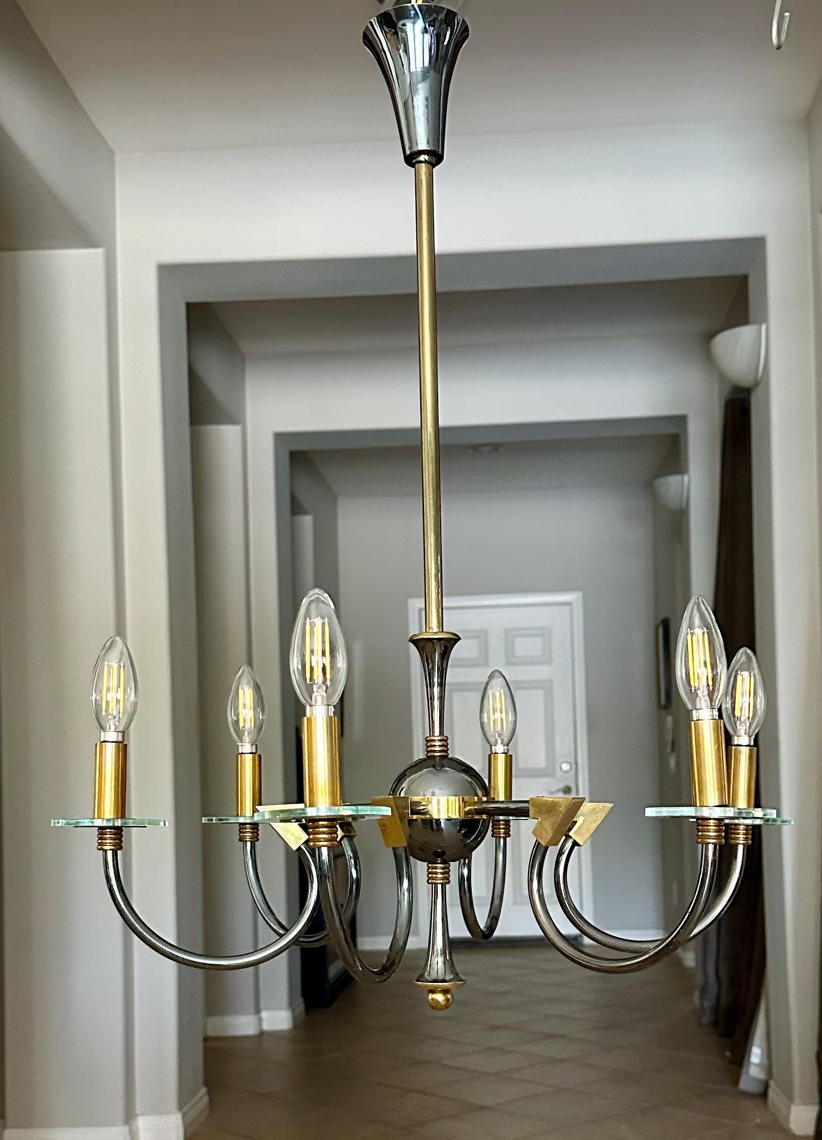 French moderne brass patinated six-arm chandelier, attributed tp Maison Lunel, France. Sleek detailing including curved arms each with glass bobeche. Uses six candelabra 