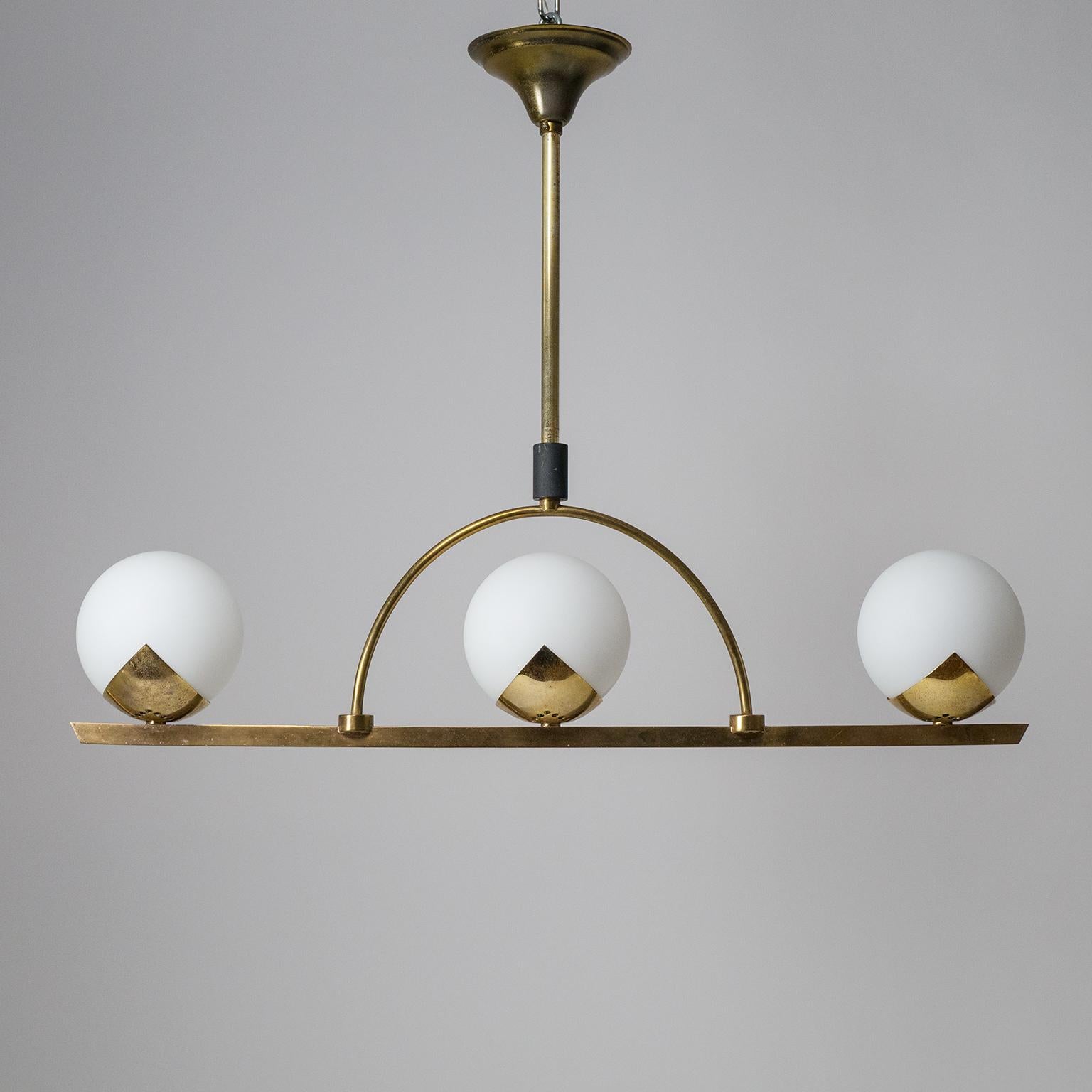 Elegant French Modern three-globe chandelier from the 1950s. Lovely minimalist brass structure with unusual 'triangular' and pierced brass supports for the satin glass diffusers. Good original condition with a nice patina on the brass. Three old