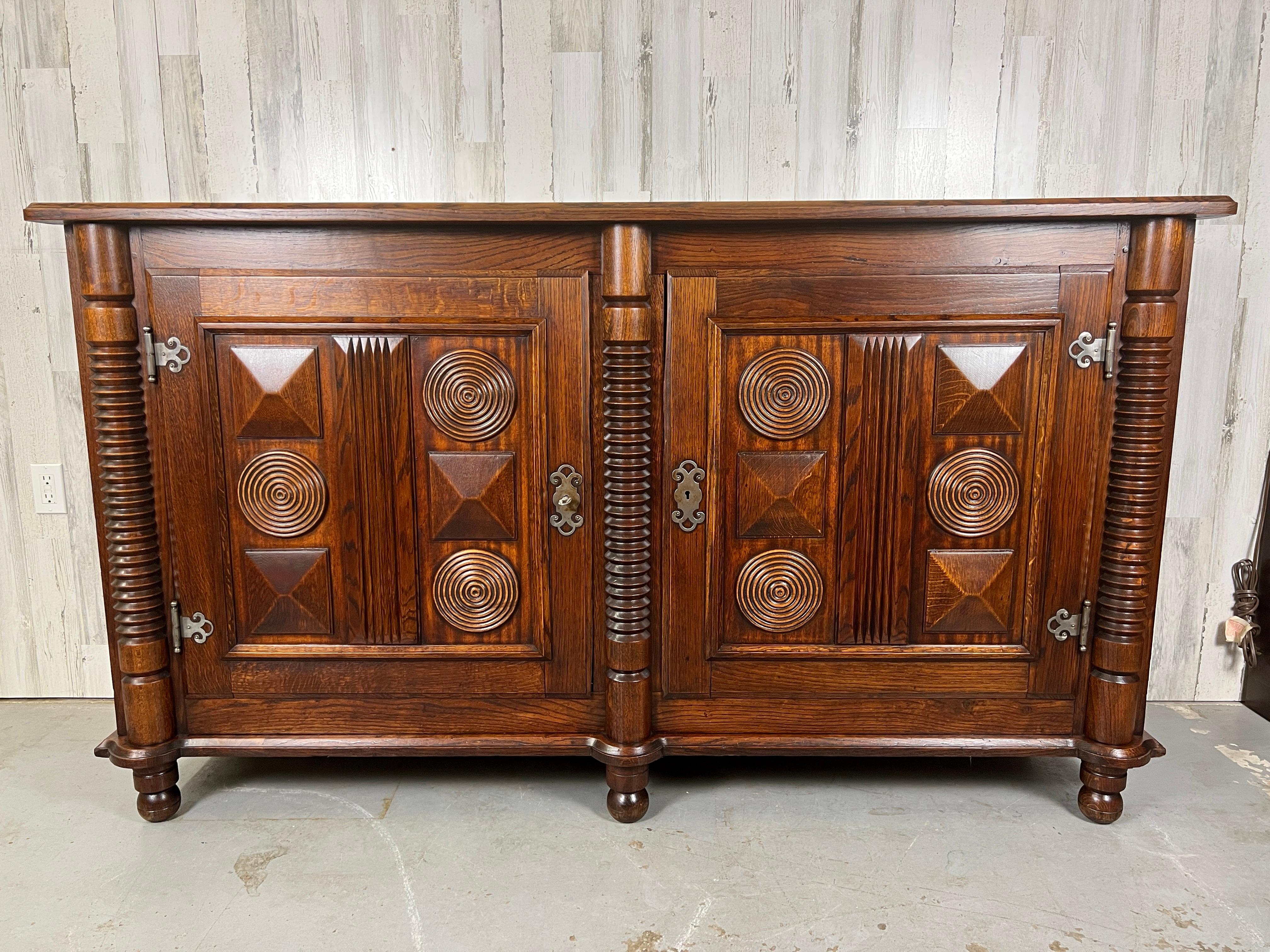 Stunning French Deco sideboard with geometric design on the doors and machine age turned columns flanking the two doors that open to two adjustable shelves. Other design features Nickel plated hinges and Escutcheons , Mortise and Tenon joints with