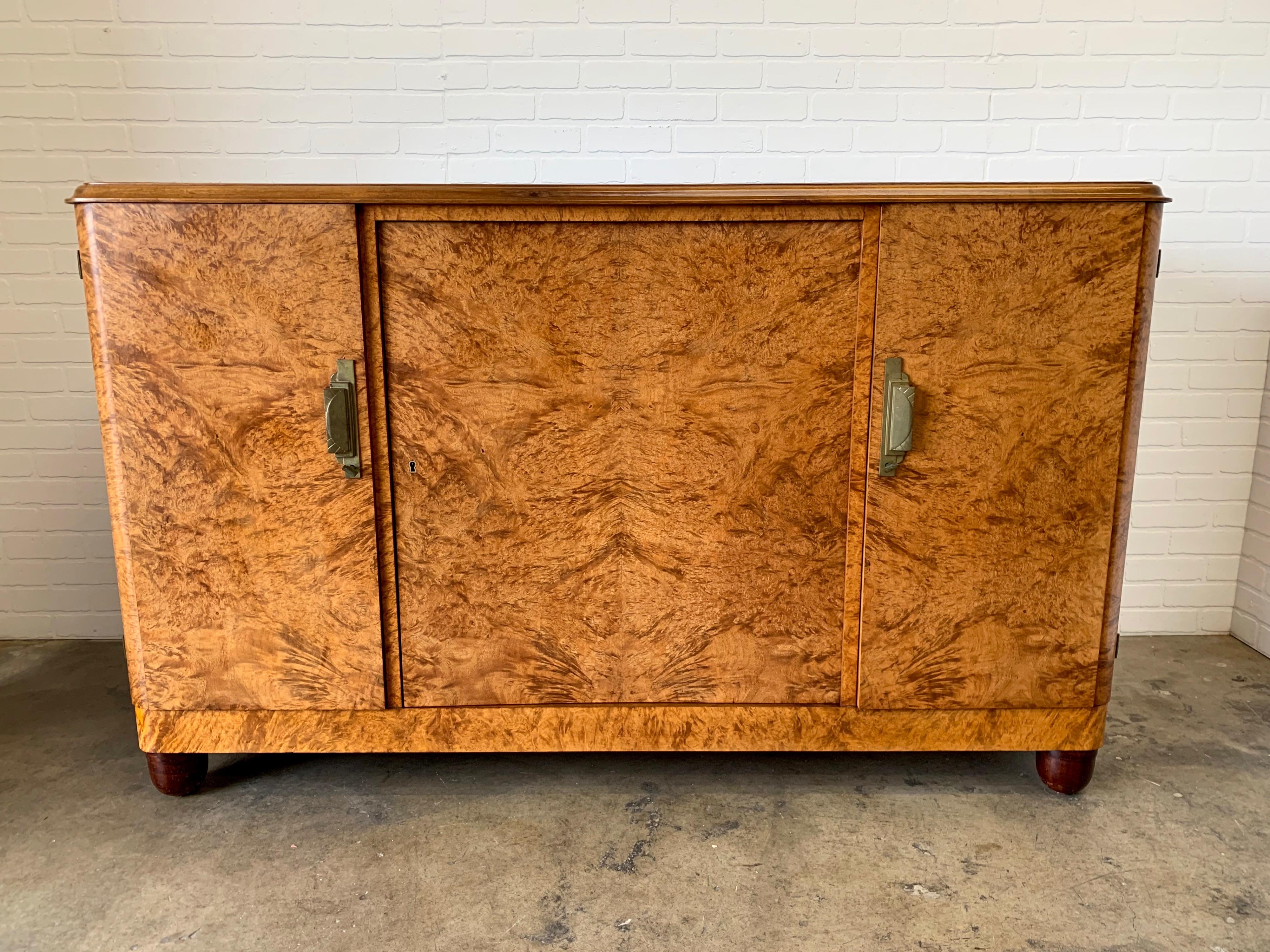 French Deco burl wood buffet with bronze hardware and black glass top
The shelf on the inside is adjustable to several heights also included is two original keys.