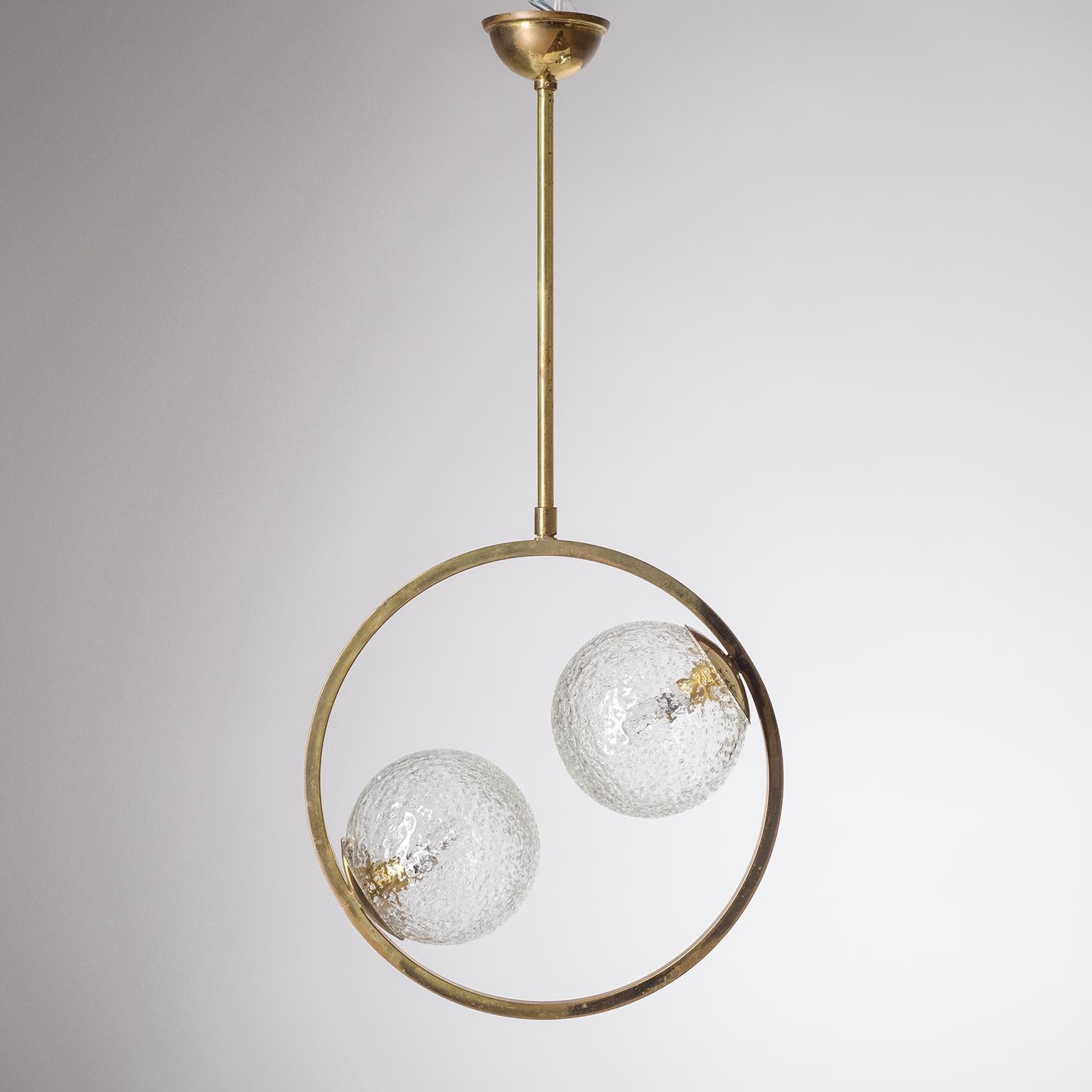 Colgante modernista francés de latón de finales de los años 50 o principios de los 60. Precioso diseño escultórico minimalista con un anillo de latón y dos globos de cristal muy texturizados, yuxtapuestos y descentrados. Dos tomas E14 de latón y
