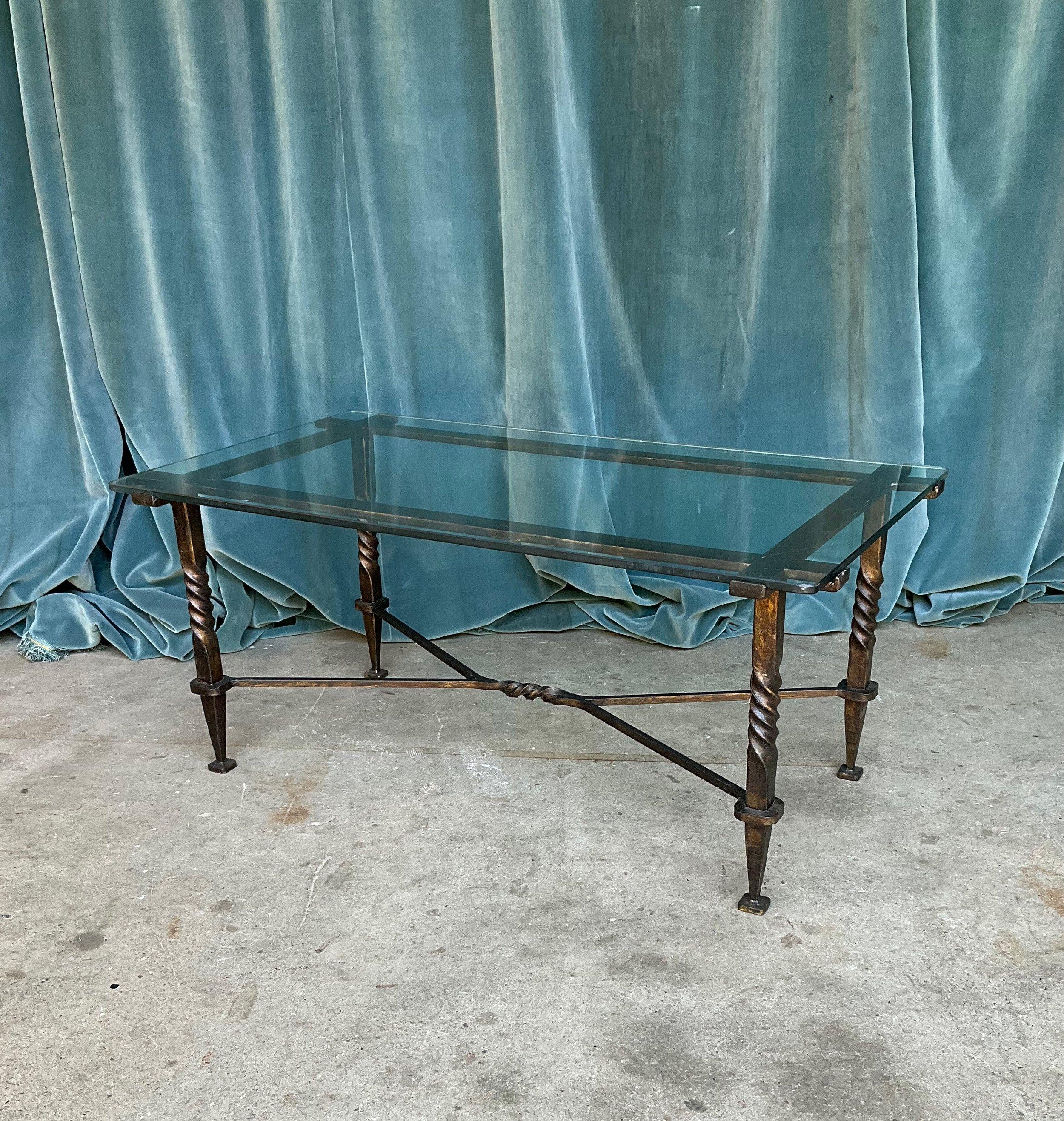 An exceptional French Modernist coffee table from the 1940s, masterfully crafted in wrought iron and clear glass. The clear glass top, featuring rounded corners, is securely held in place by eight extended iron elements that not only provide