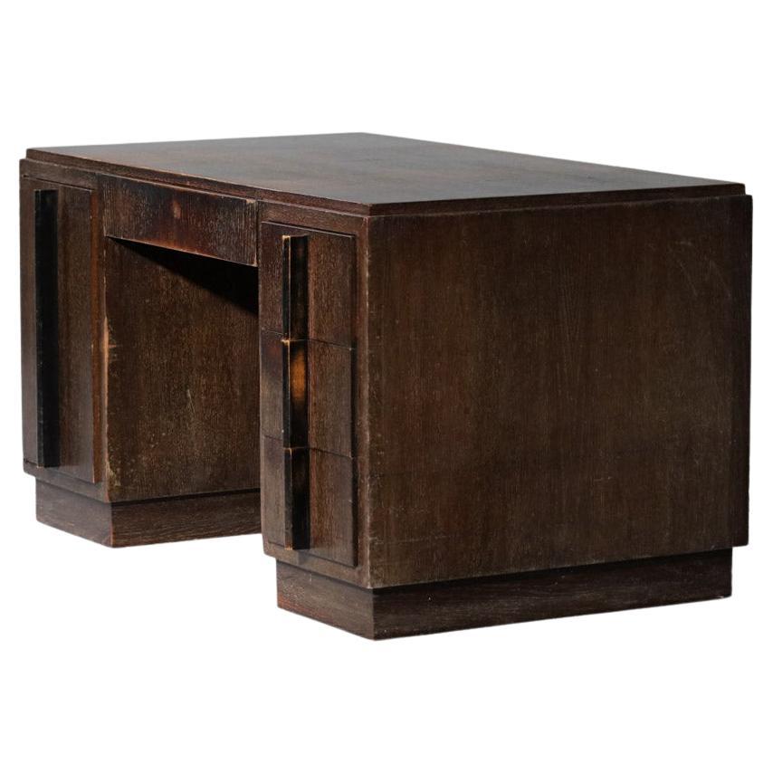 Imposing modernist desk of the 50s in the taste of the work of Jean Michel Frank. Structure in solid oak and veneer, ceruse work on the whole desk. It is composed of three lateral drawers, a central one and a swinging door opening on a shelf.