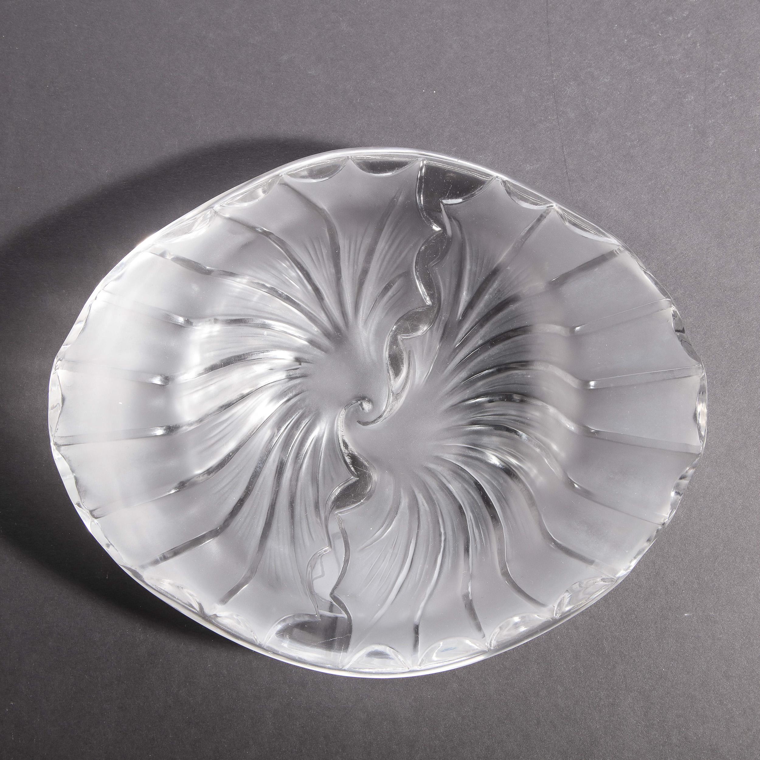 This elegant modernist decorative bowl was realized by Lalique- one of the world's most storied and celebrated makers of crystal and luxury goods since 1817 in France- during the latter half of the 20th Century. It offers a slightly convex form with