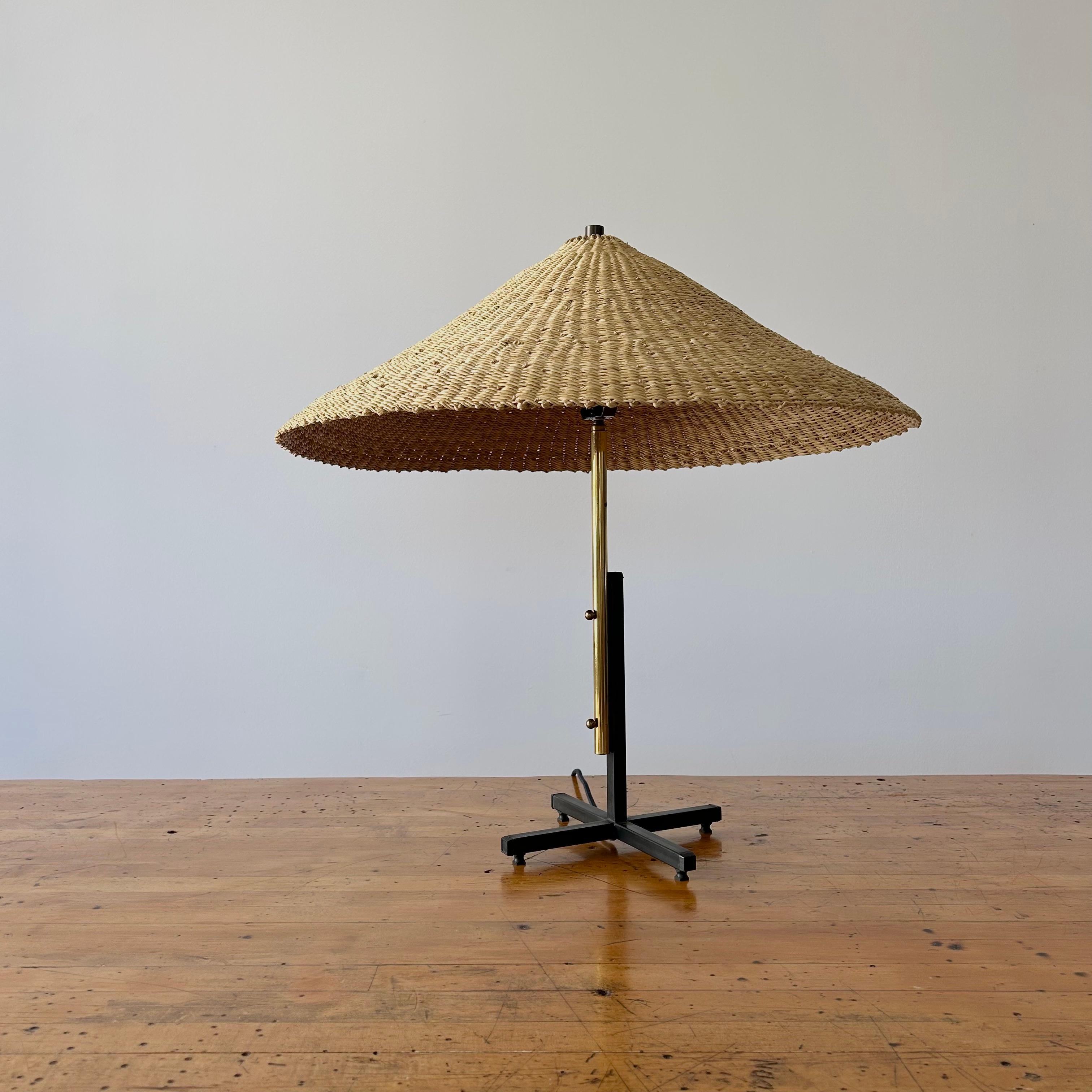 An elegant Modernist table lamp from France circa 1950s. Generously sized iron and brass base in good vintage condition with some small scratches and dings. Rewired in LA and reimagined with an elephant grass shade. 

Light shade handwoven by a