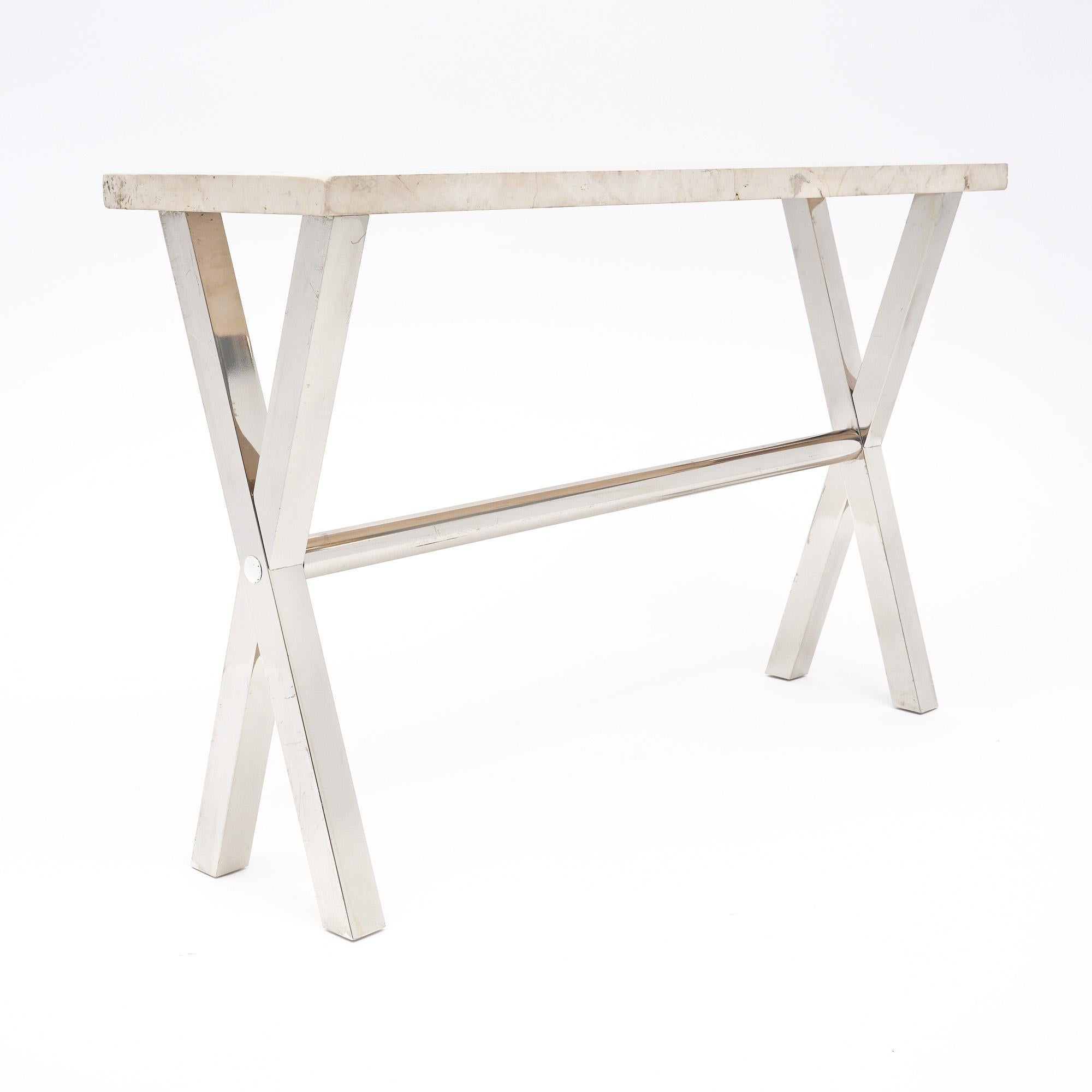 Console table from France. This piece features a base of chrome finished steel. The base has two x-shaped legs with a long circular stretcher between. It supports a thick “Travertin
