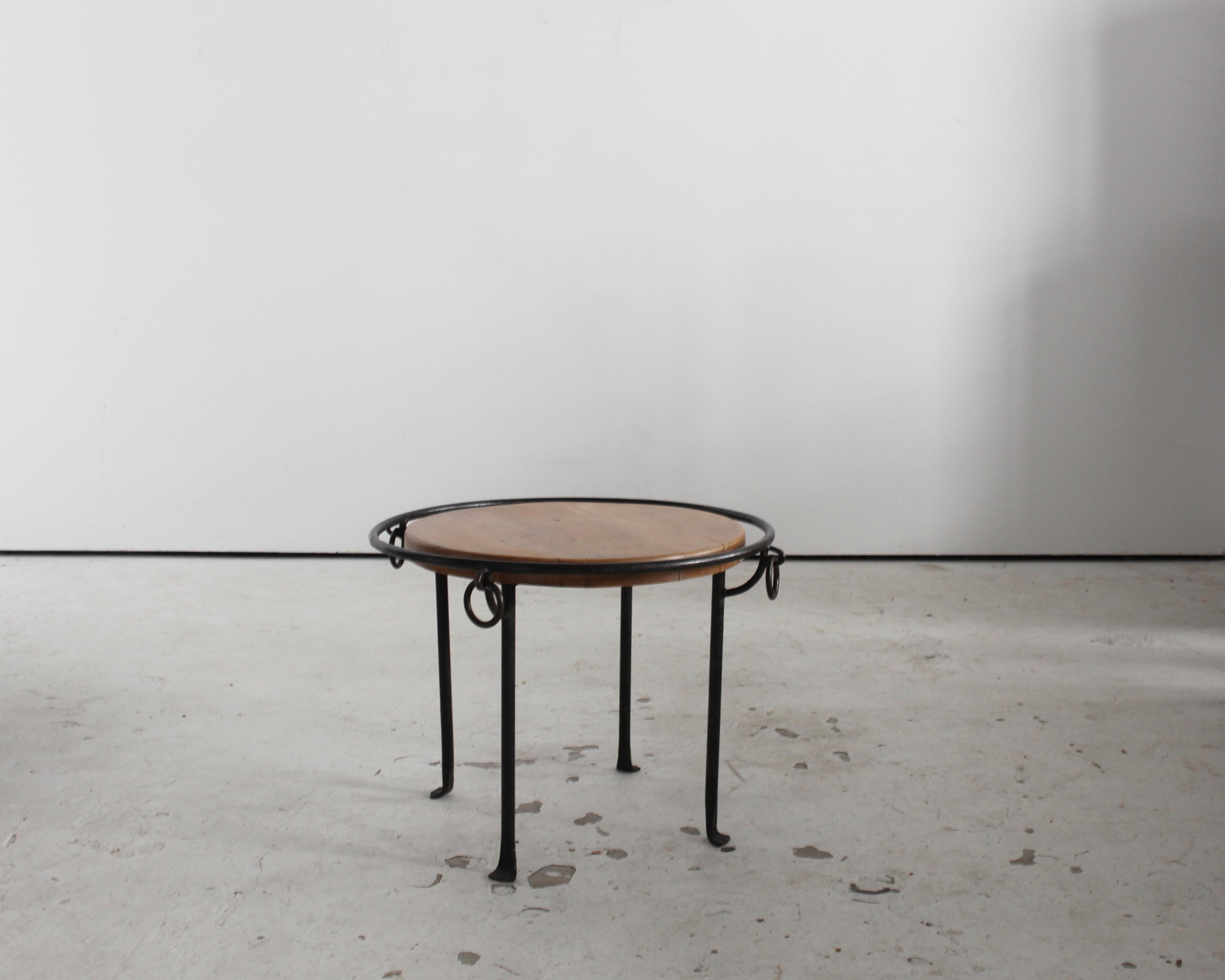 Table basse circulaire moderniste française des années 1950, avec structure en fer forgé et plateau en chêne décapé.
