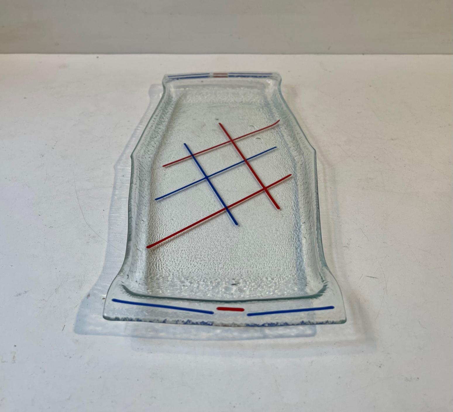 Dekoratives flaches Tablett zum Servieren oder Ausstellen von Sektgläsern, Parfüms, Lotionen etc. Sie besteht aus handgeformtem, strukturiertem Glas und ist mit roten und blauen Emaille-Linien handbemalt, die ein geometrisches Muster ergeben.
