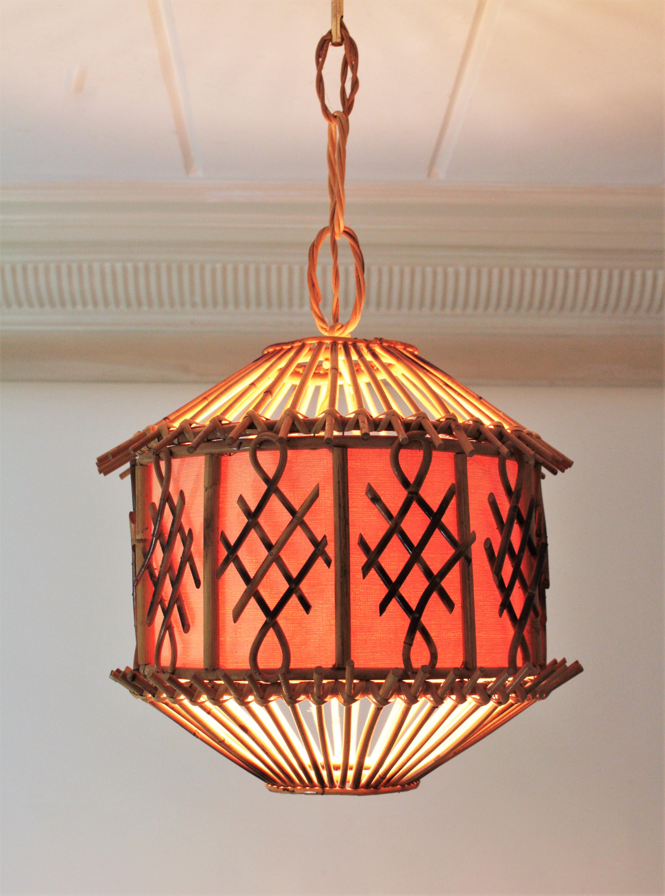 Mid-Century Modern rattan and wicker pendant or lantern accented by Oriental Details. France, 1950s-1960s.
This handcrafted ceiling lamp features a rattan pagoda shaped lantern with chinoiserie decorations and an inner paper shade. It hans from a