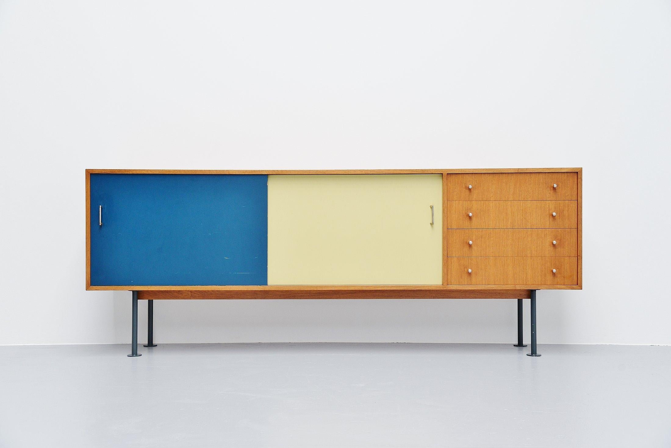 Fantastic modernist sideboard made by unknown designer or manufacturer, France, 1950. The sideboard is made of walnut wood and has yellow and blue sliding doors with a shelve behind. On the right there are 4 drawers. The legs are made of blue