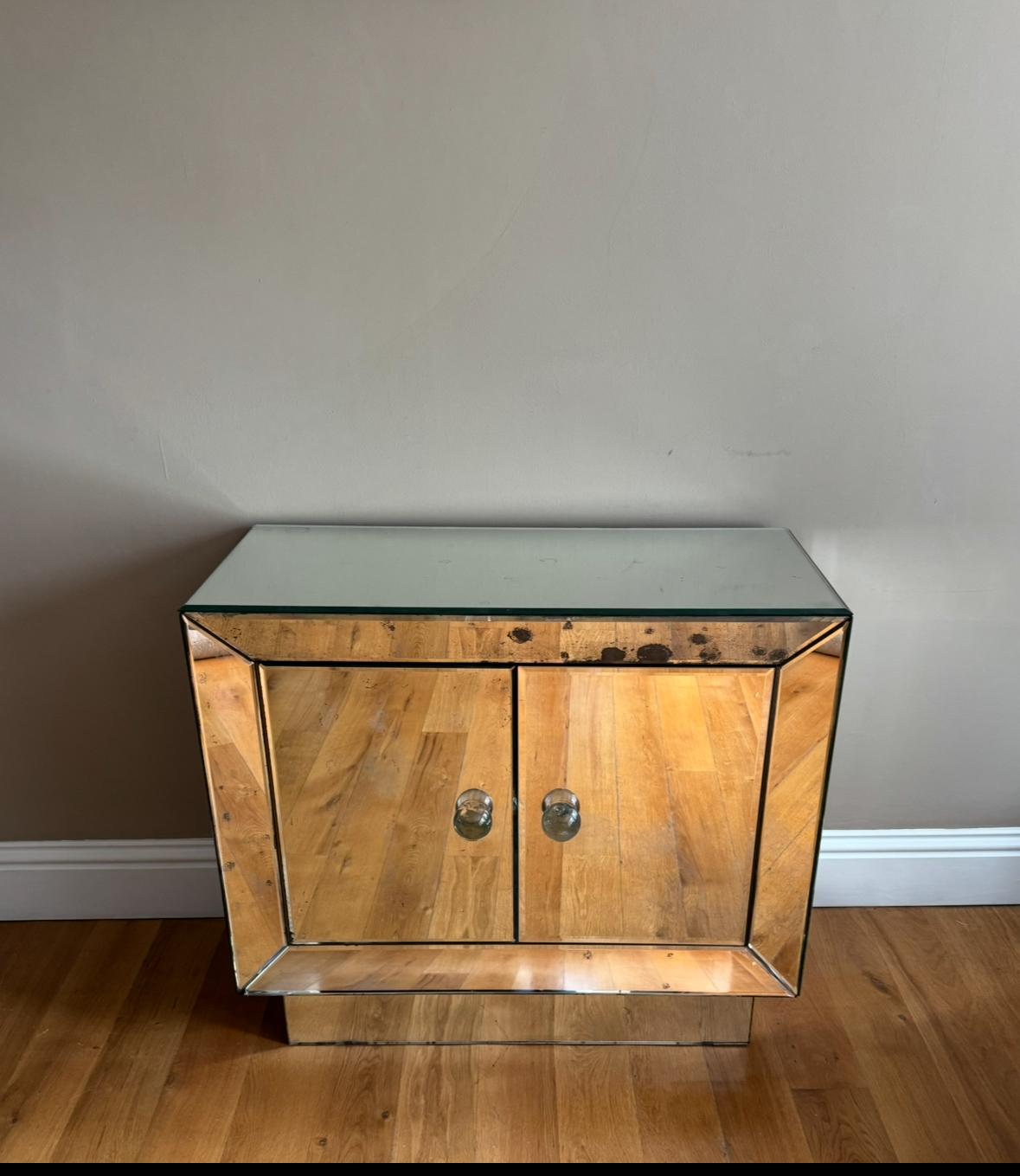 Bellissimo piccolo mobile francese modernista a due ante a specchio con un ripiano interno e fantastiche maniglie a sfera in vetro massiccio. Un'anta a specchio è stata sostituita e ci sono due piccole scheggiature agli angoli. Nello stile di