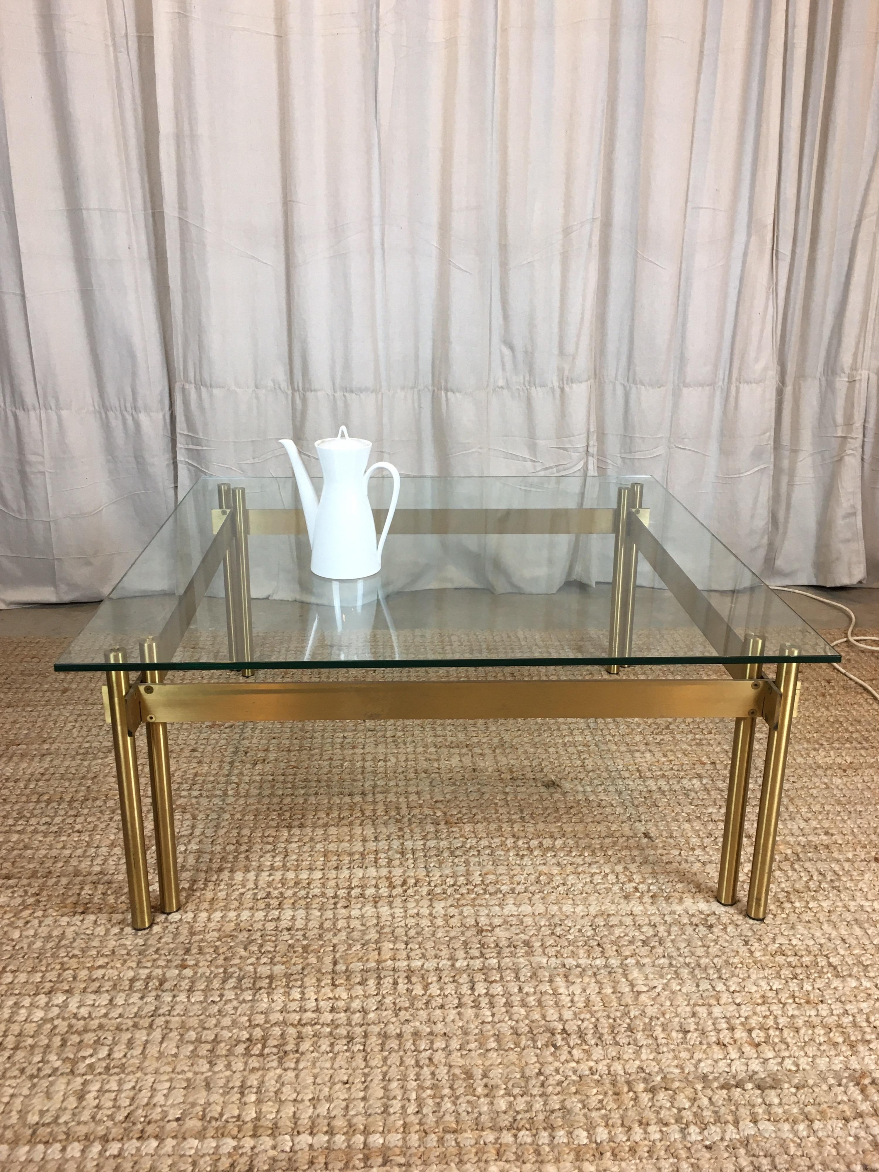 A 1970s, Mid-Century Modernist brass and clear glass coffee table of high quality and excellent proportions. 

The solid brass legs and crossed bars have an attractive brushed finish. A thick plate glass top with finely beveled edges completes