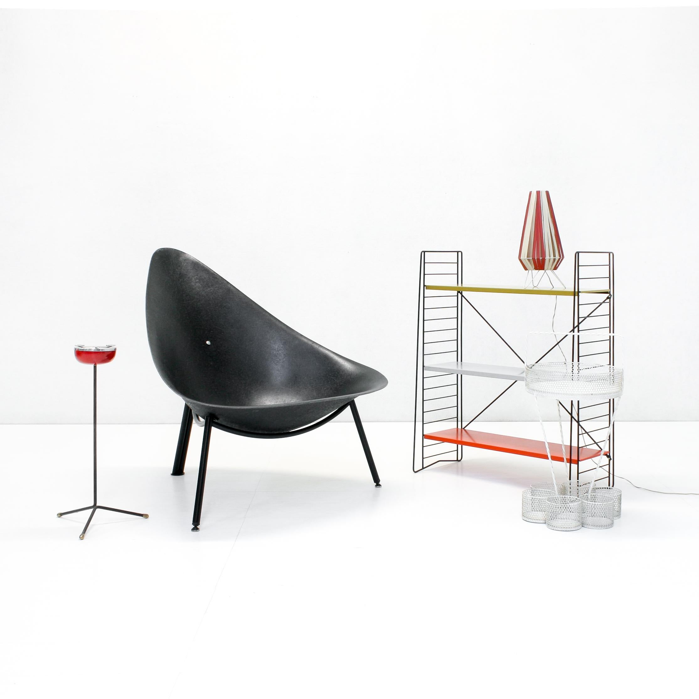 The Mérat fiberglass lounge chair, originally designed in 1956 comes in a black shell on a black steel tube tripod frame.

This version is more recent but shows a clearly visible strong fibre structure and does have the vintage French mondernist