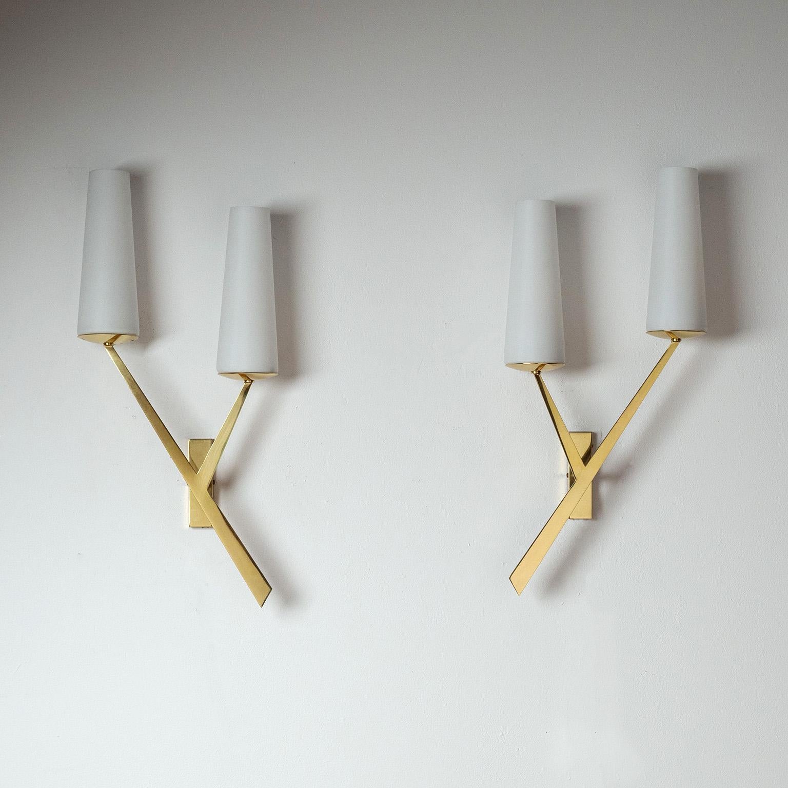 Pareja de grandes apliques modernistas franceses de los años 50, atribuidos a Arlus. Dinámica estructura de dos brazos de latón pulido con dos difusores cónicos de cristal satinado cada uno. Totalmente restaurada, con dos enchufes E14 cada uno con