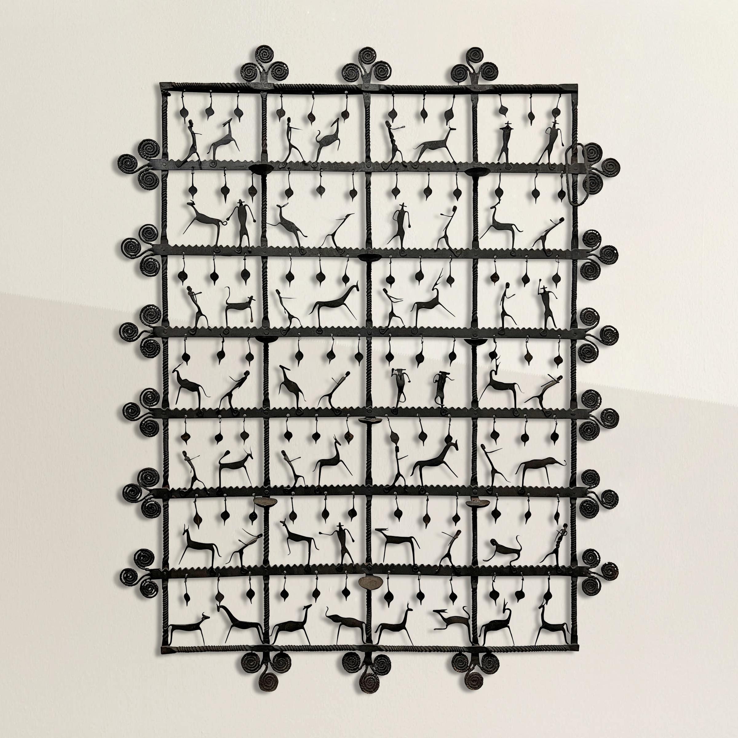Step into the enchanting world of French 1950s modernism with an exquisite hand-wrought iron wall sculpture from the esteemed Atelier de Marolles. This masterpiece, intricately constructed in a grid pattern of 28 squares, unfolds a visual narrative