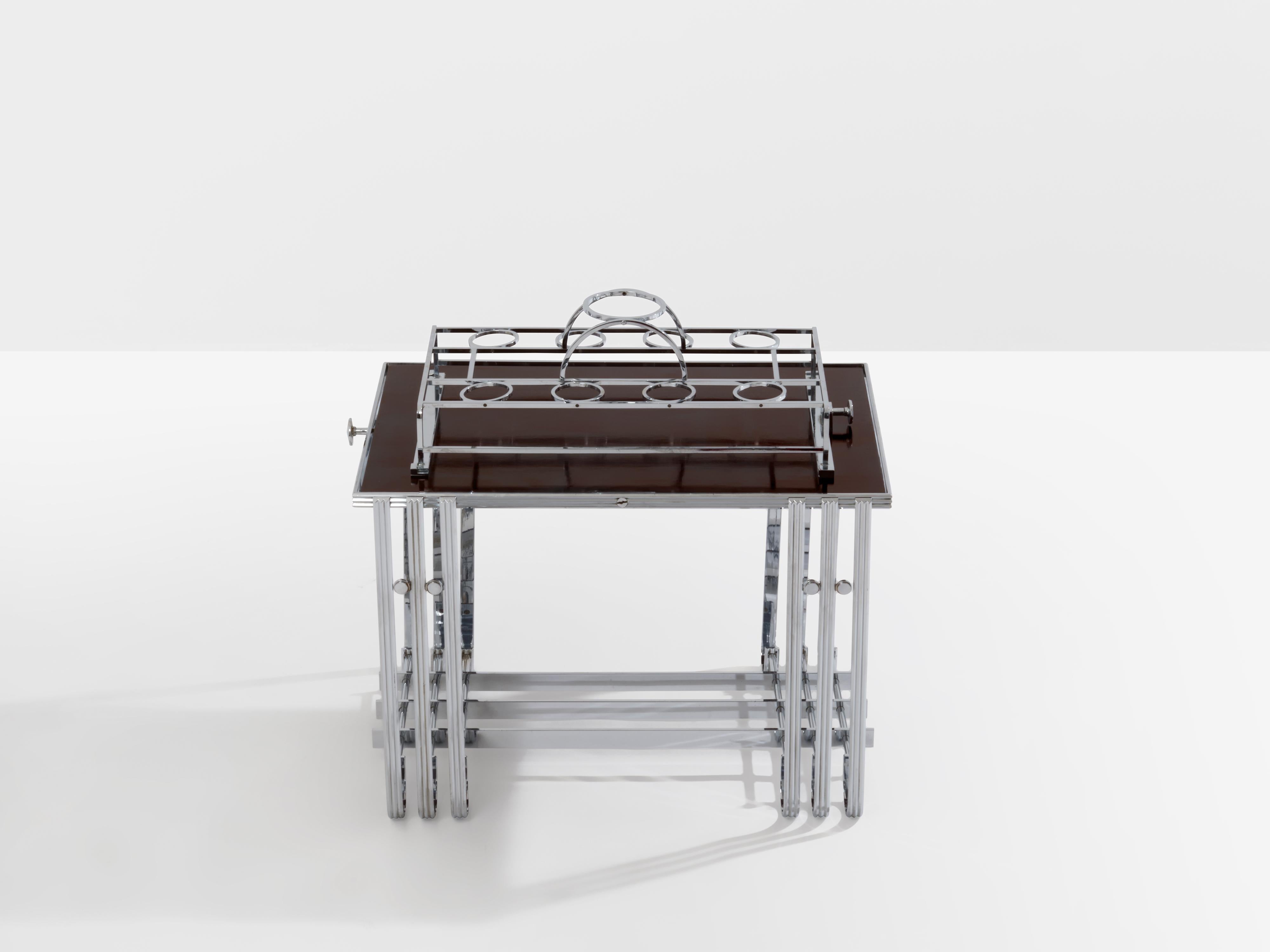 This is a nice nickel-plated bar table produced in France in the 1930s. The walnut top can swivel with a handle, one side holding one bottle holder and 8 glass holders, all nickel-plated. These tables were used in yachts to prevent glasses from